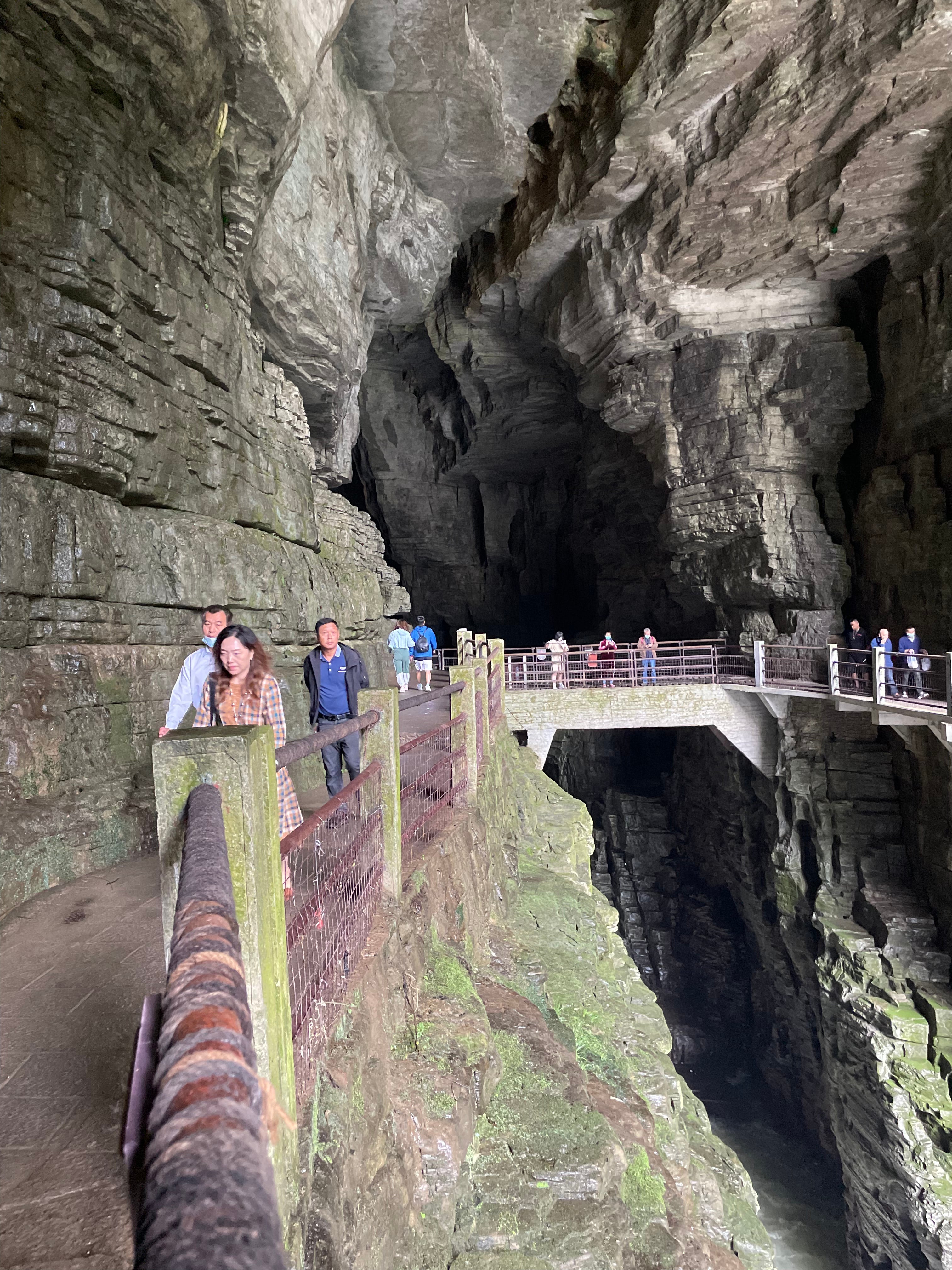 Tourists pass over a bridge above where the Qing River flows through Tenglong Cave