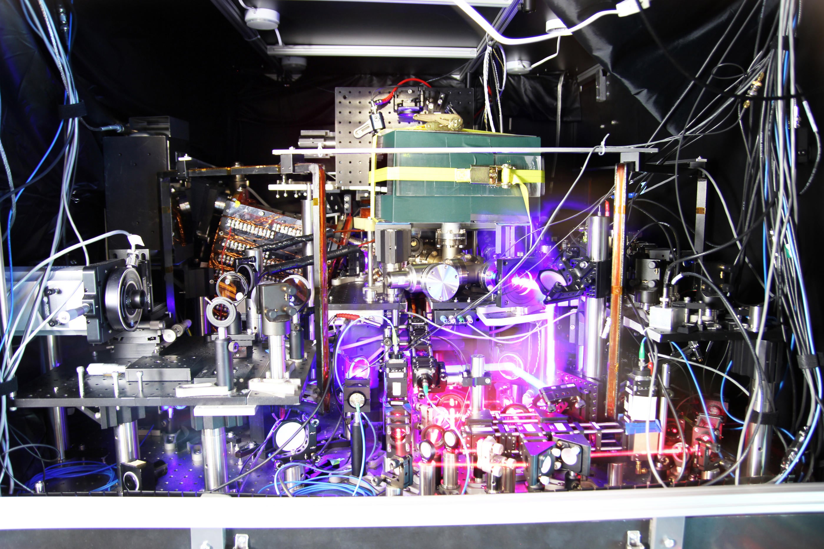 JILA’s experimental atomic clock based on strontium atoms held in a lattice of laser light is the world’s most precise and stable atomic clock. The image is a composite of many photos taken with long exposure times and other techniques to make the lasers more visible.
