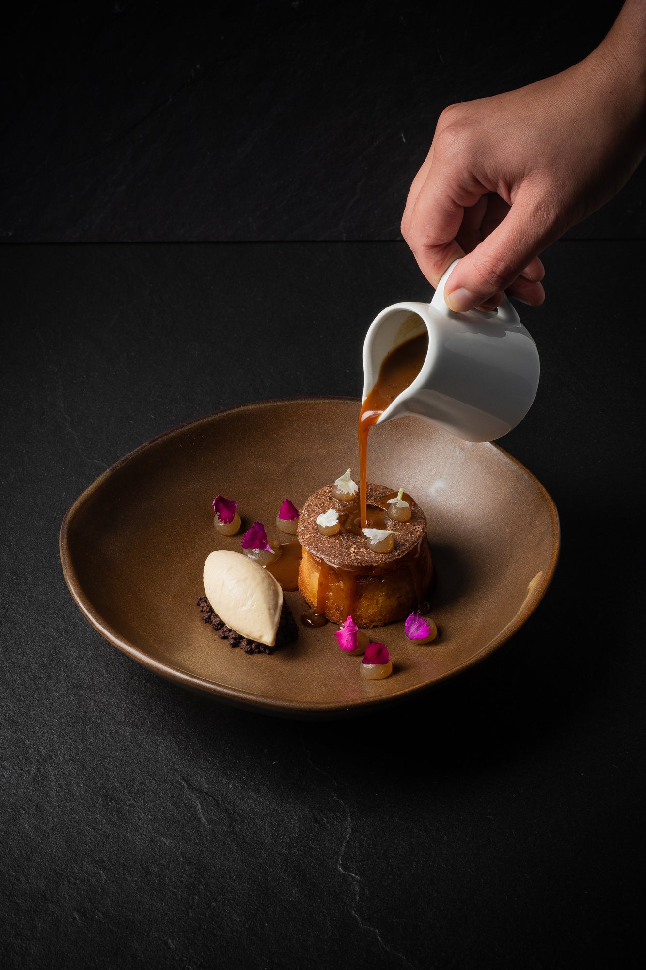 A Hiakai dessert of warm brown butter and pear cake, cocoa husk opaline, chocolate crumbs, roasted parsnip ice cream drizzled with horopito butterscotch