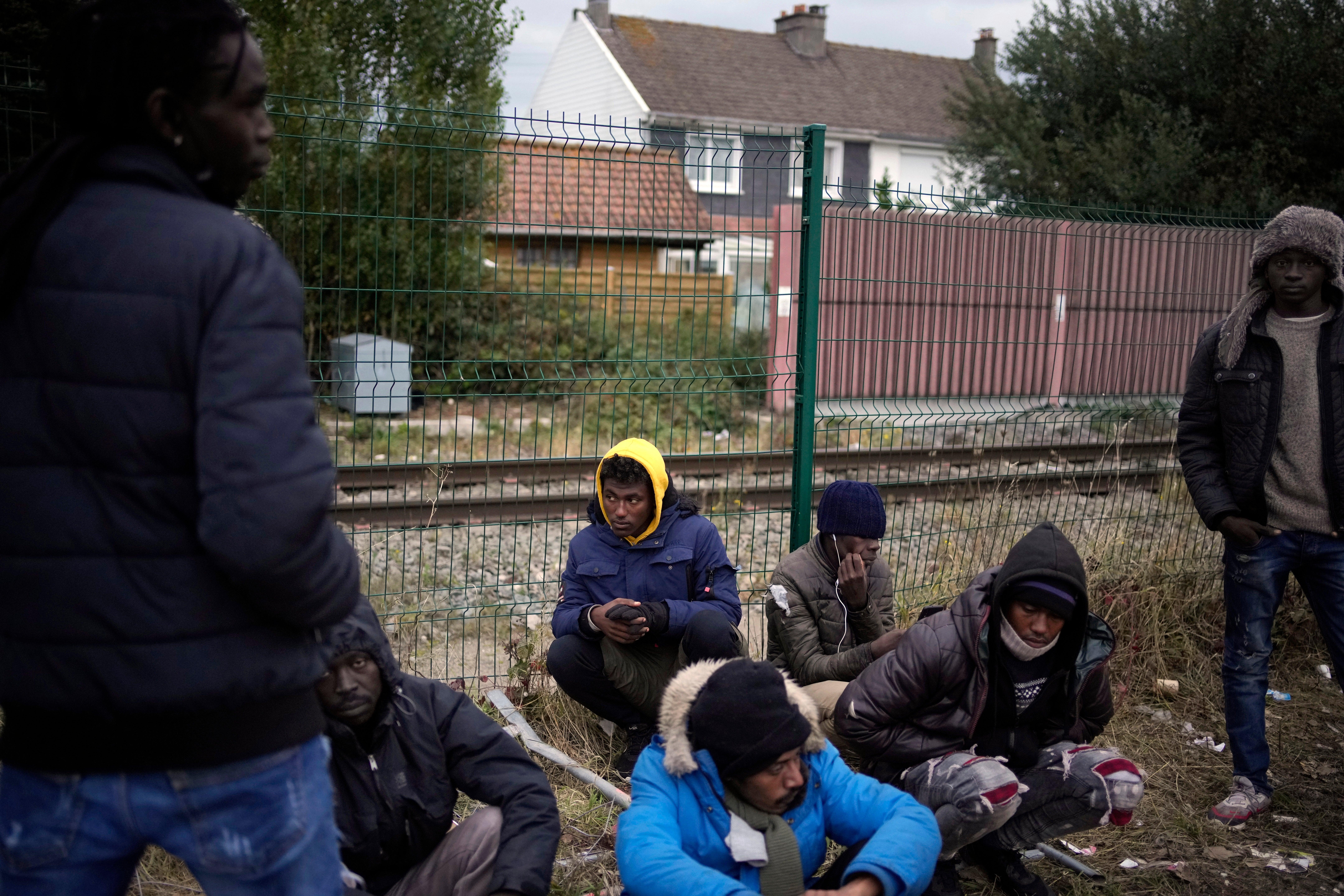 Migrants and refugees wait for food distribution at a camp in Calais