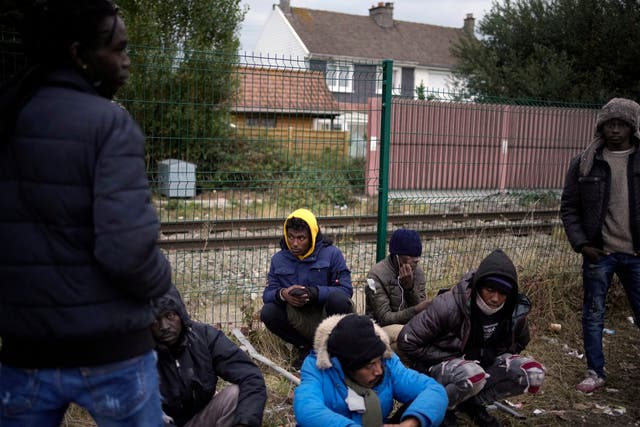 <p>Migrants and refugees wait for food distribution at a camp in Calais</p>