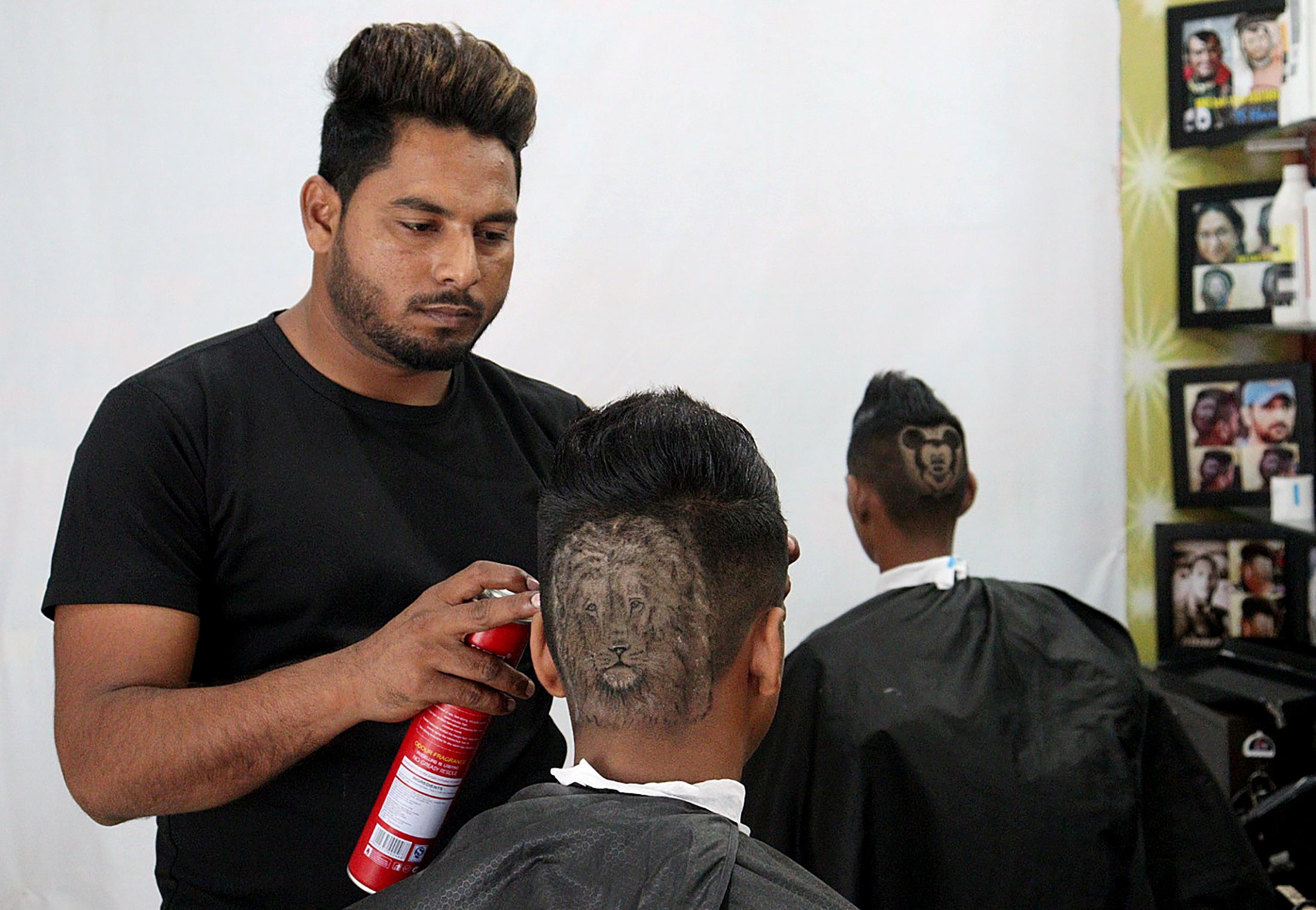 Gurwinder Singh Sidhu shapes the hair of a customer into a lion inside their shop in Dabwali town