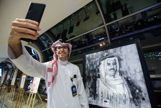 <p>A Kuwaiti man takes a selfie with a portrait of late emir Sheikh Sabah al-Ahmad al-Jaber al-Sabah</p>
