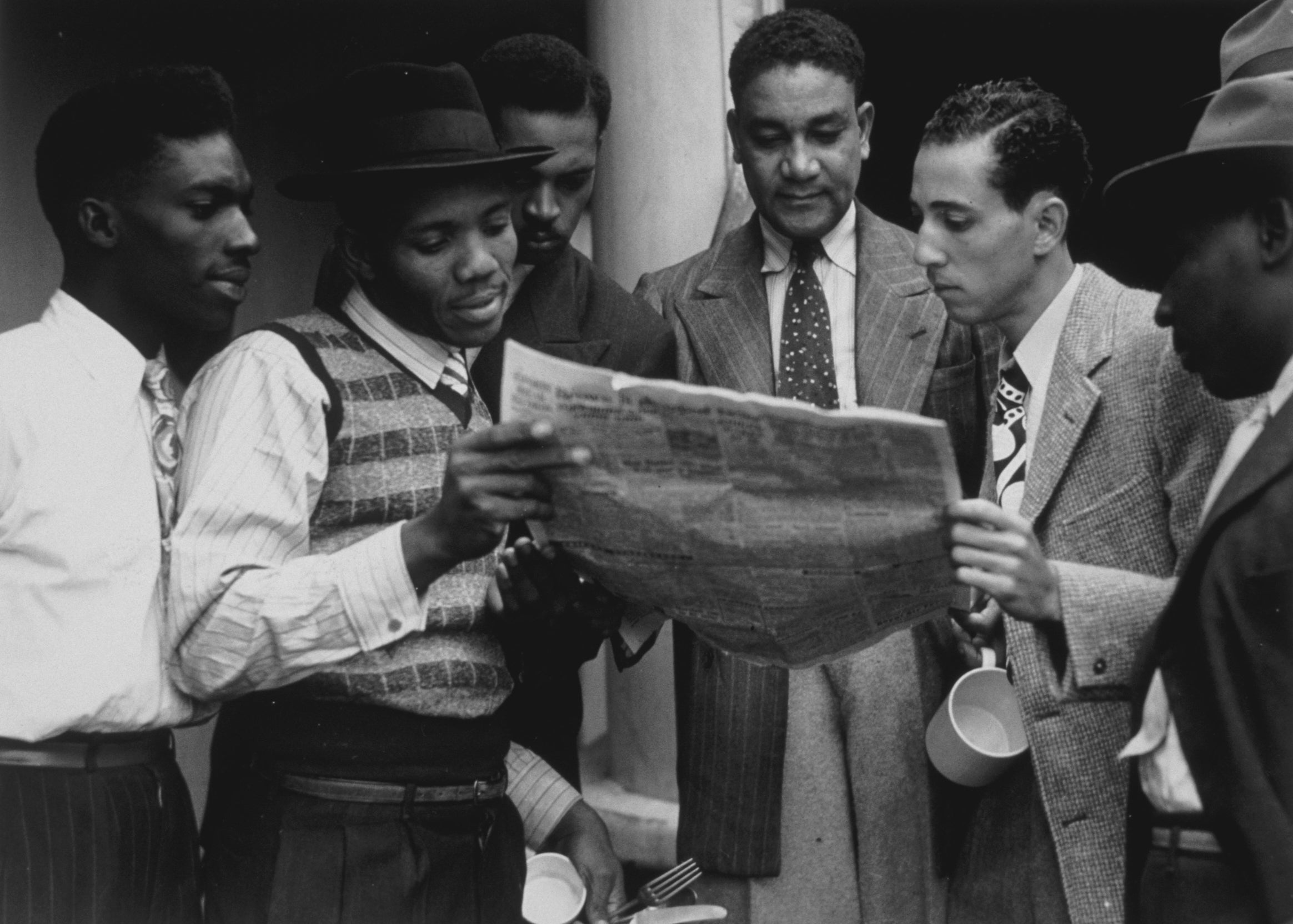 Jamaicans reading a newspaper aboard ex-troopship 'Empire Windrush' bound for Tilbury docks in Essex