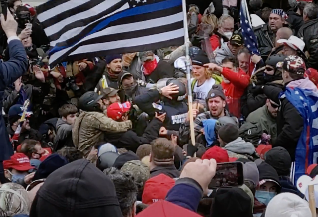 <p>Officer Michael Fanone being assaulted by pro-Trump mob beneath a ‘Blue Lives Matter’ flag outside the US Capitol on 6 January 2021</p>