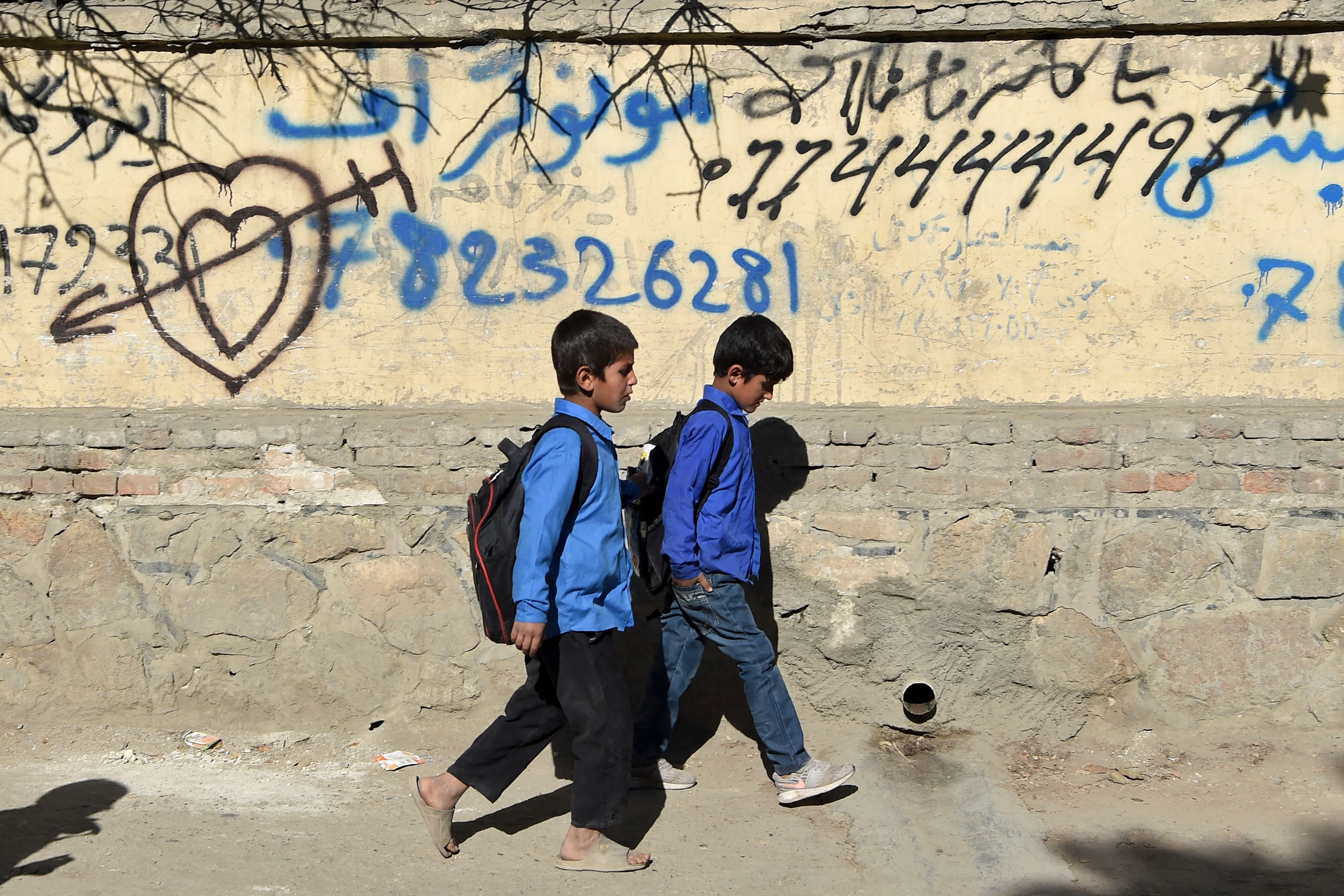 <p>Children walk home after attending school along a roadside in Kabul, October 2021 </p>