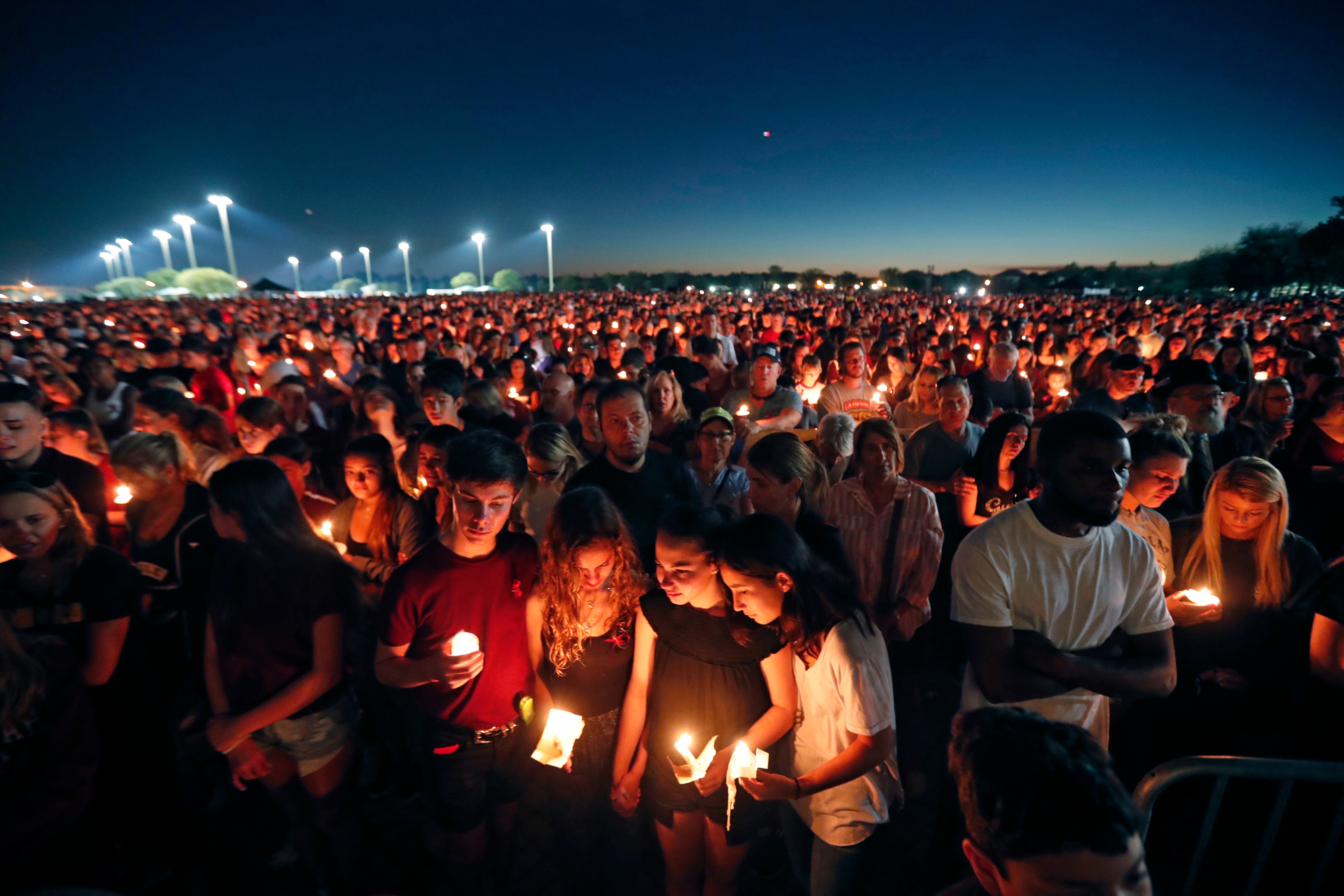 People hold a vigil for the 17 victims of the Parkland shooting