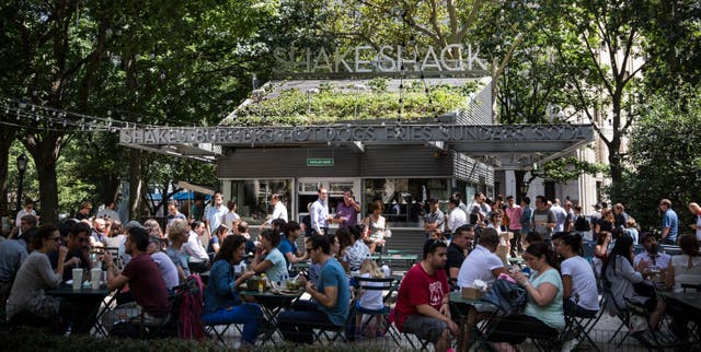 <p>People sit outside the original Shake Shack in Madison Square Park in New York City</p>