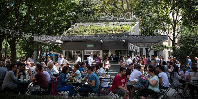 <p>People sit outside the original Shake Shack in Madison Square Park in New York City</p>