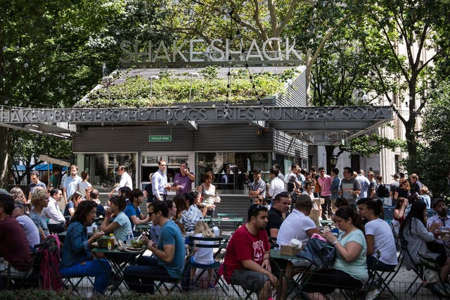 <p>People sit outside the original Shake Shack in Madison Square Park in New York City</p>