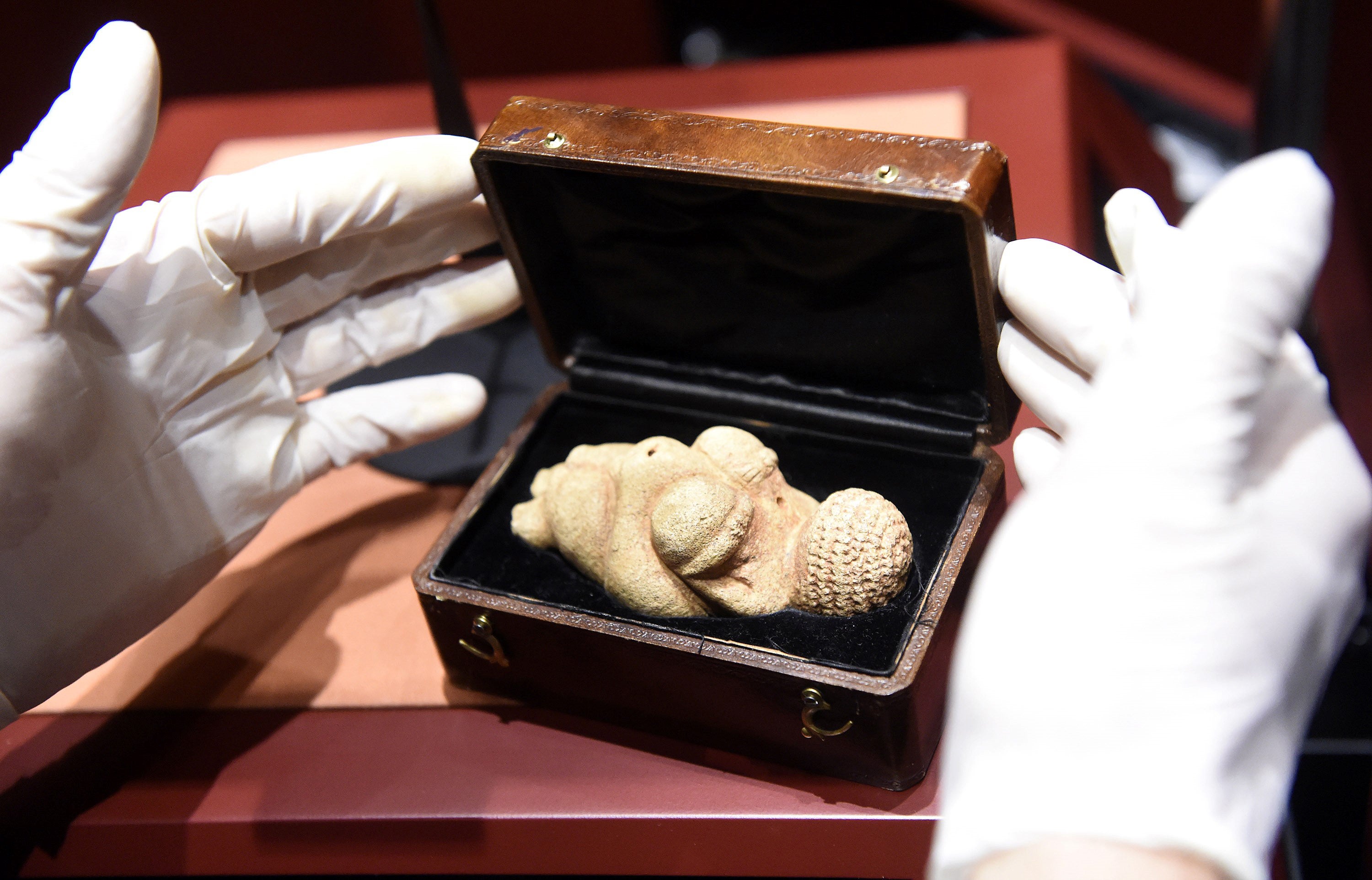 File: This undated picture released on 28 February 2018 shows the hands of a person opening a box containing the ‘Venus of Willendorf’ figurine at the Nature Historical Museum, that was censored by Facebook