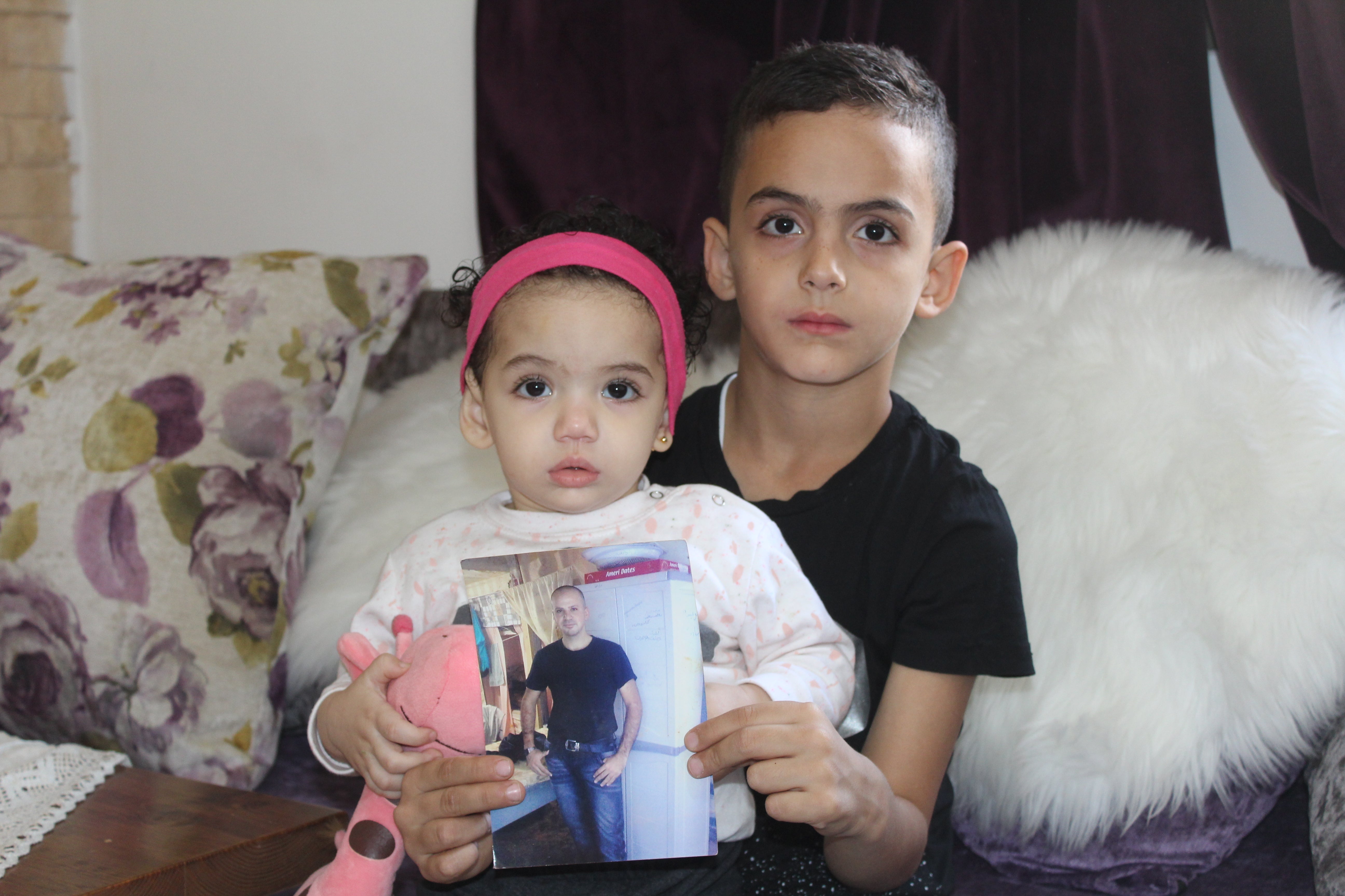 Son Mohammad and daughter Nour holding a photo of their father Shadi Abu Aker, currently detained by Israel