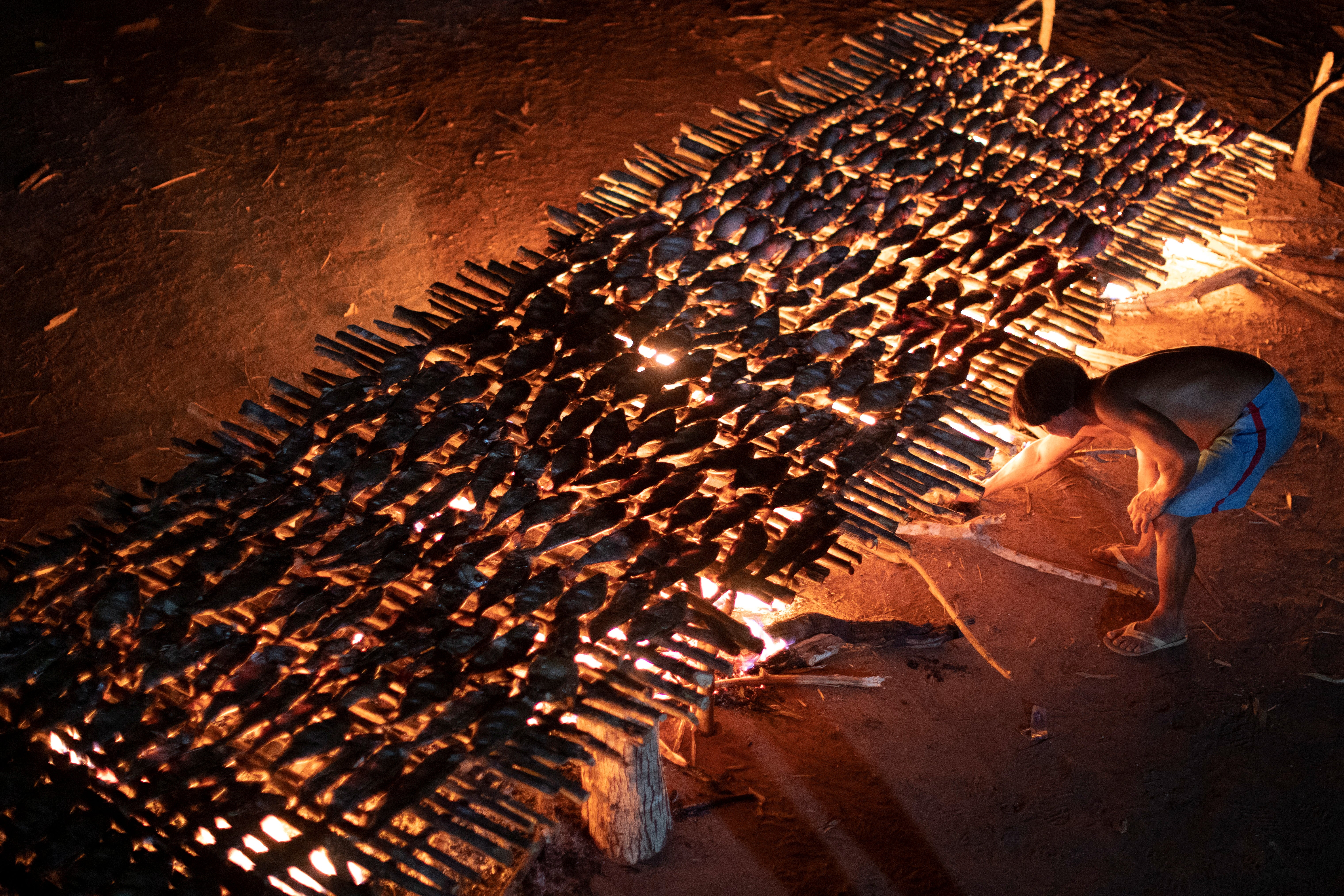 A Yawalapiti man cooks fish during the Kuarup funeral ritual