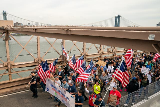 La gente marcha a través del Puente de Brooklyn para protestar por el mandato de la vacuna Covid-19 para los trabajadores municipales el 25 de octubre de 2021 en la ciudad de Nueva York.