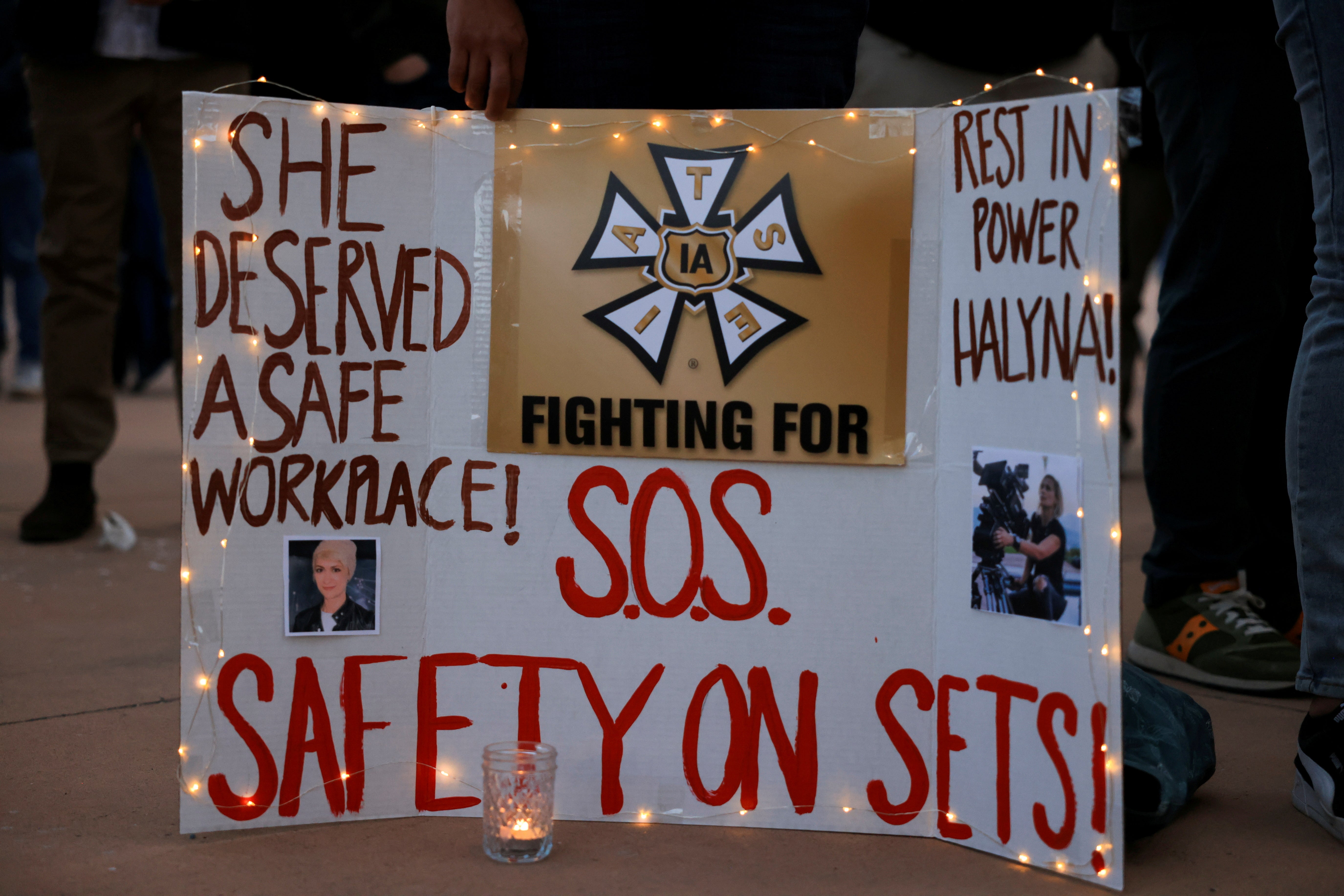 A woman displays a sign calling for workplace safety at the vigil