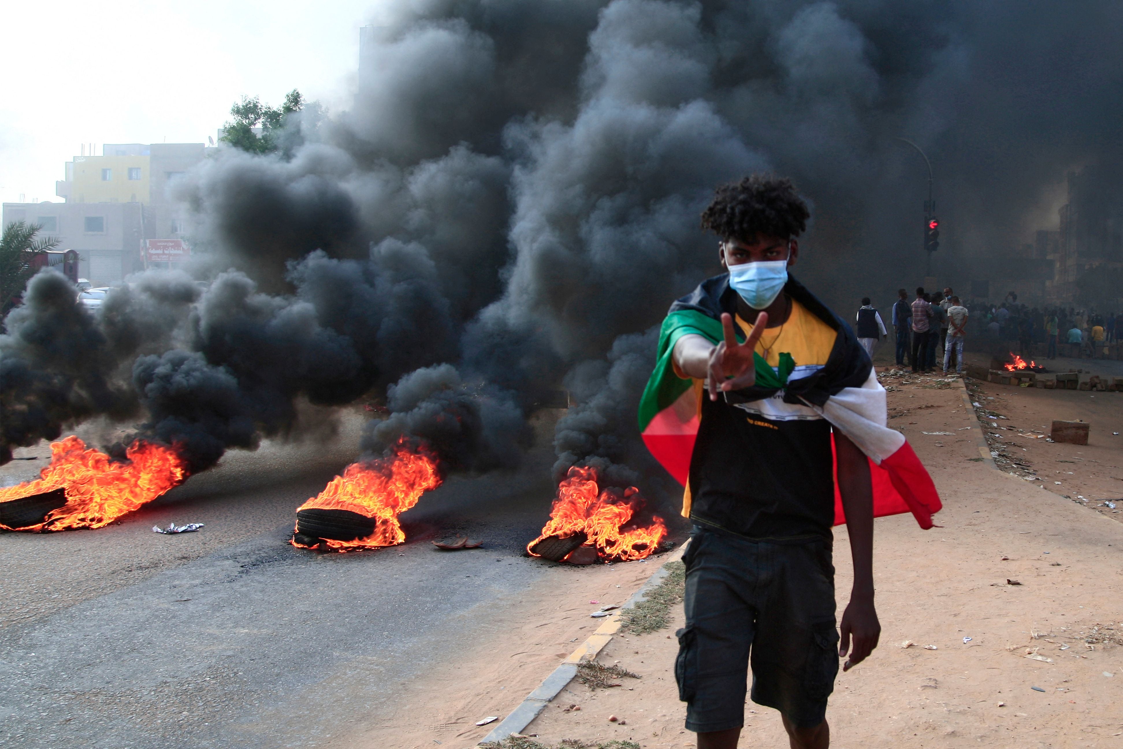 A Sudanese protester draped with the national flag flashes the victory sign