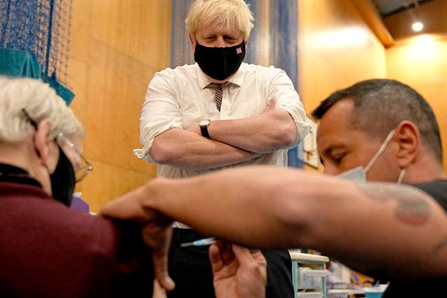 <p>Boris Johnson watches as a man receives a booster jab in west London last week </p>