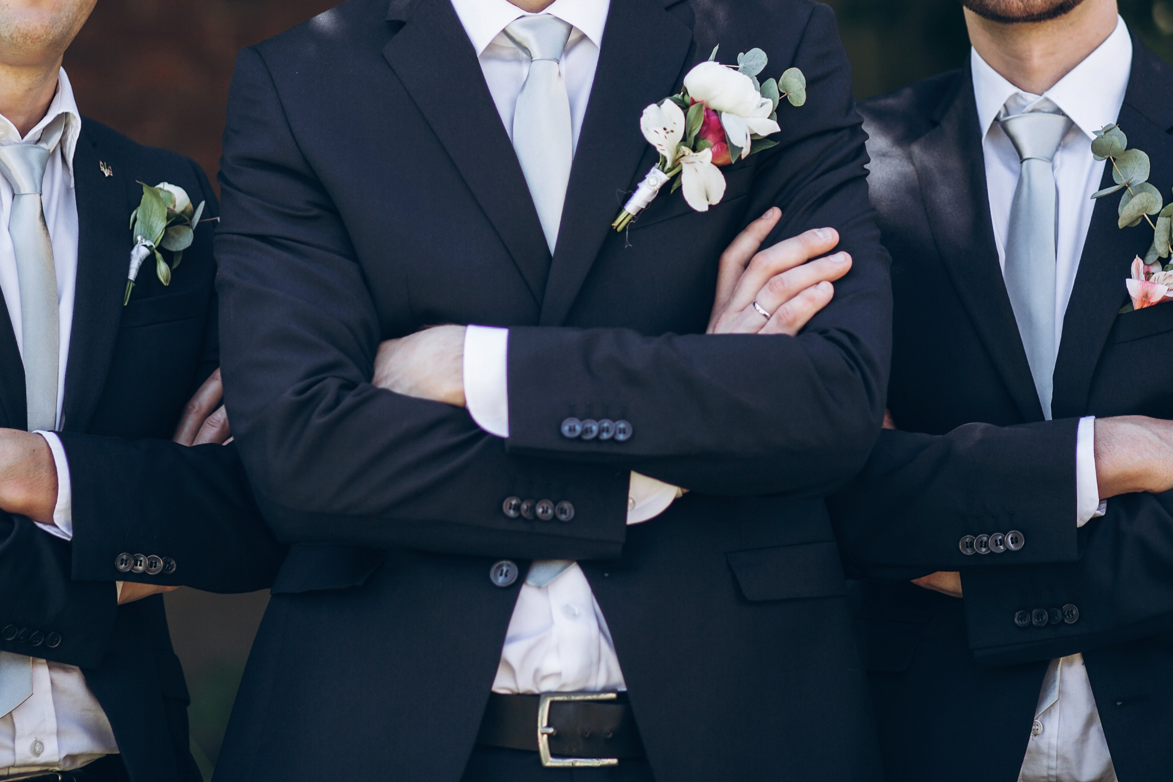 A froom in suit posing with groomsmen in garden on wedding day