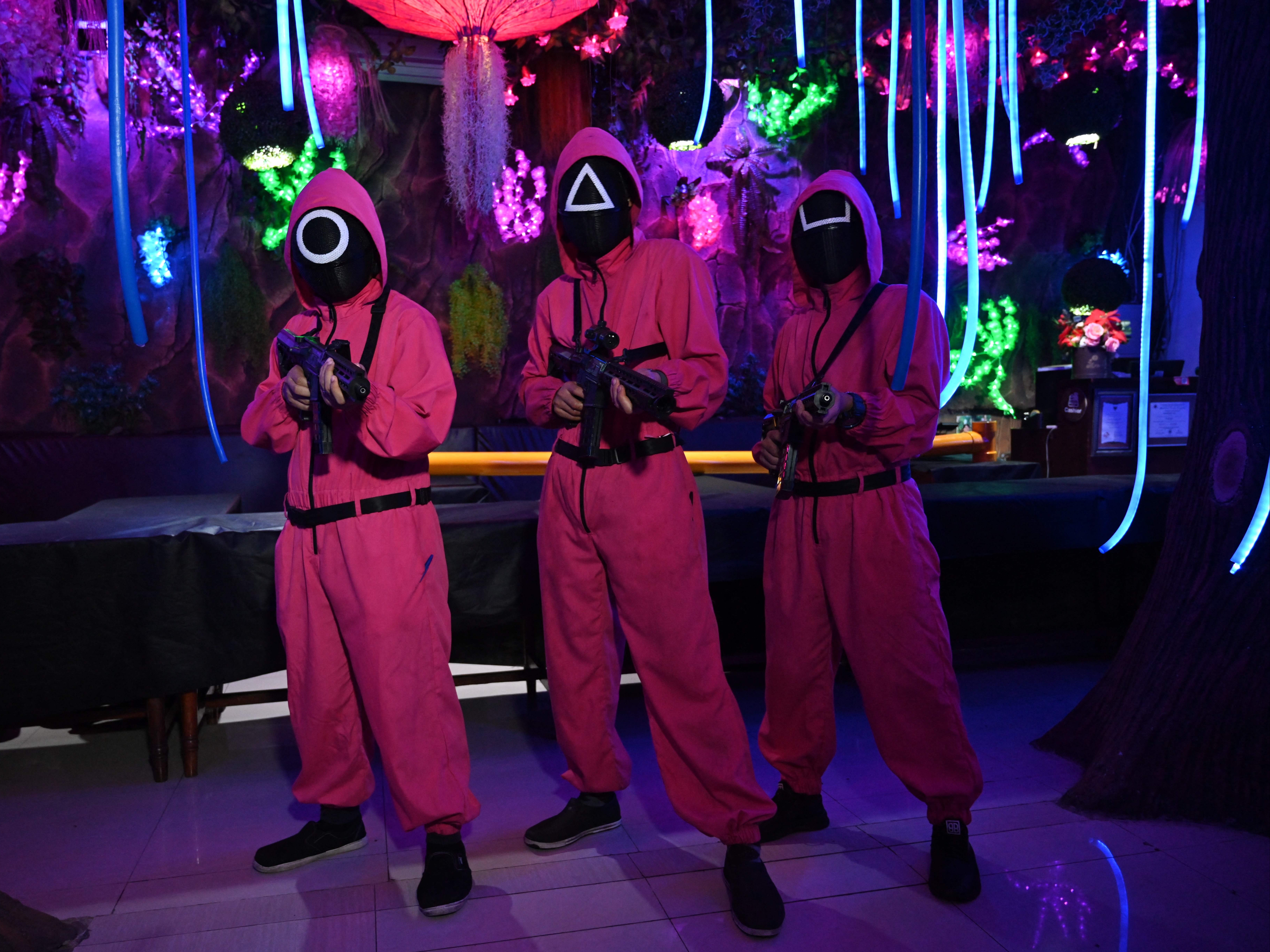 <p>Waiters dressed in outfits from the Netflix series Squid Game pose while playing a game to attract customers at a cafe in Jakarta on October 19, 2021</p>