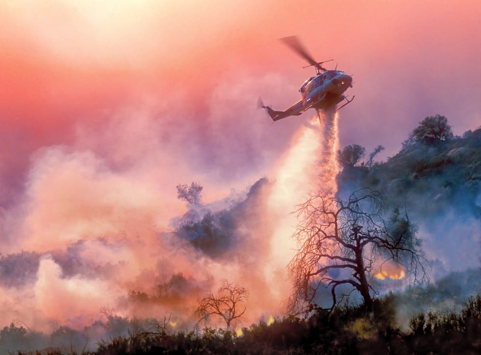<p>A helicopter dropping water on a California wildfire. Extreme weather is worsening with every fractional increase in warming, the scientists warned</p>