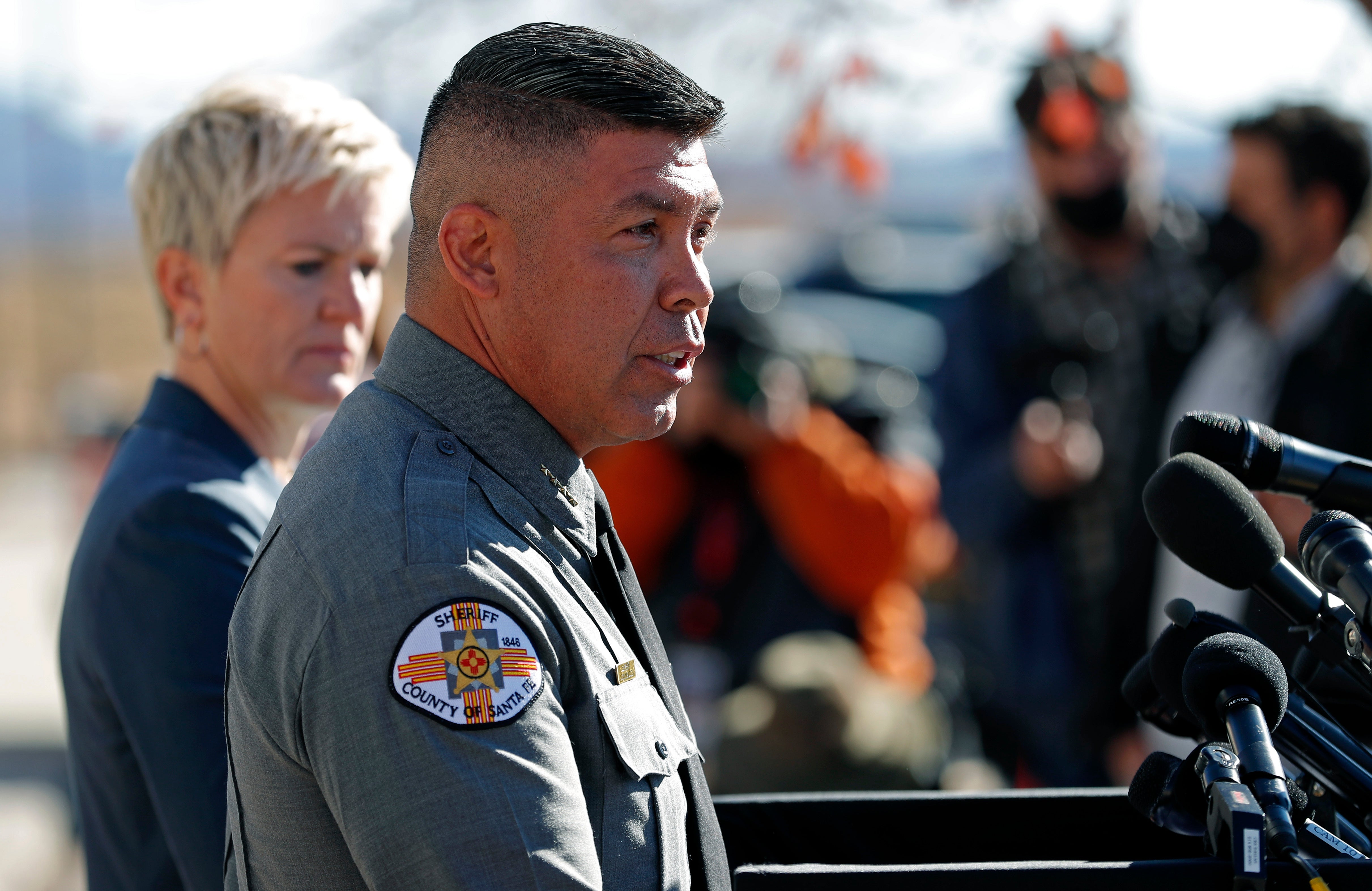 Santa Fe County Sheriff Adan Mendoza, front, speaks Santa Fe District Attorney Mary Carmack-Altwies, rear, listens during a news conference in Santa Fe, N.M., Wednesday, Oct. 27, 2021.