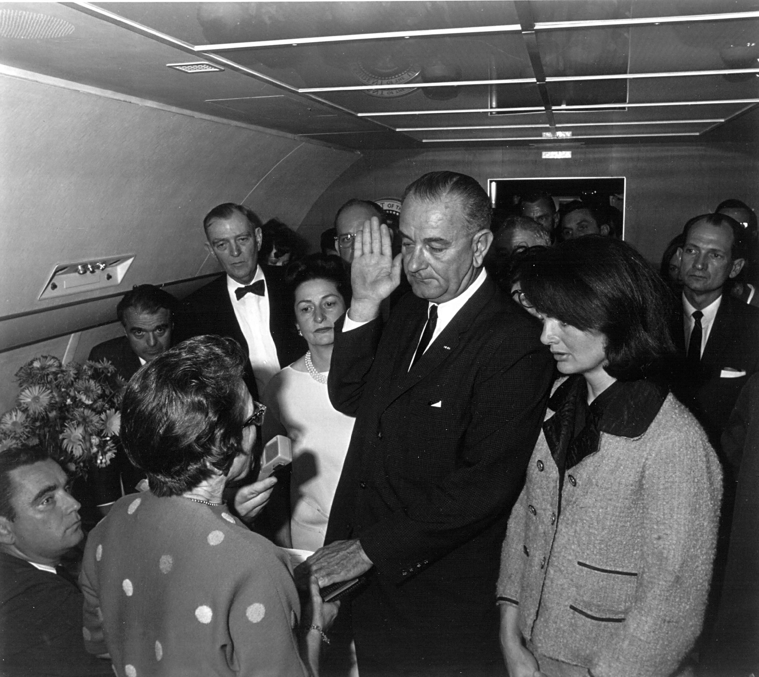 Jacqueline Kennedy (right) watches as US District Judge Sarah Hughes (second from left) administers the oath of office to President Lyndon Johnson (center)