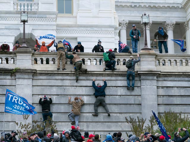 <p>Trump supporters scale the walls of the US Capitol on 6 January 2021</p>