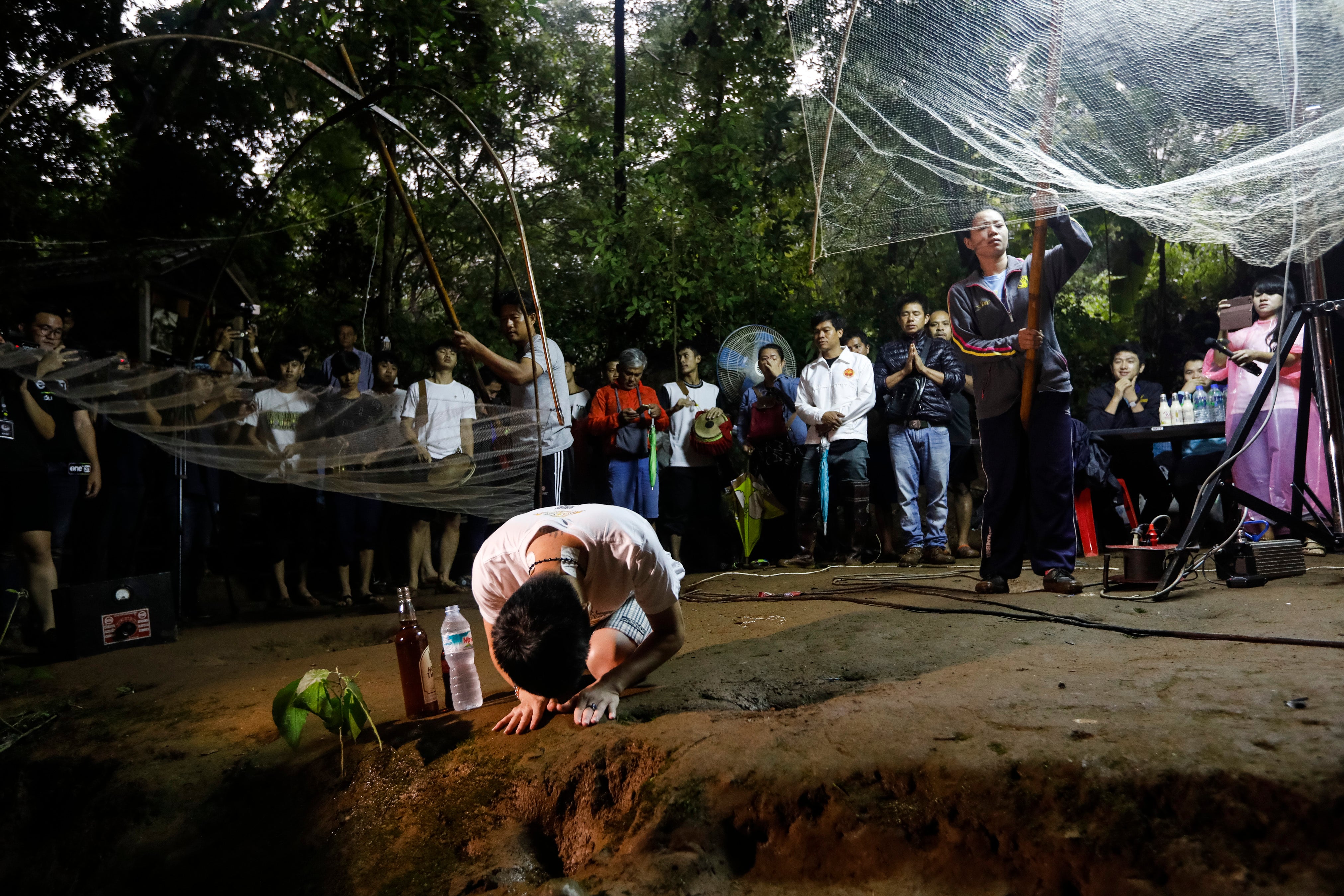 Family members and relatives pray at the entrance of Tham Luang cave while rescue personnel conduct operations
