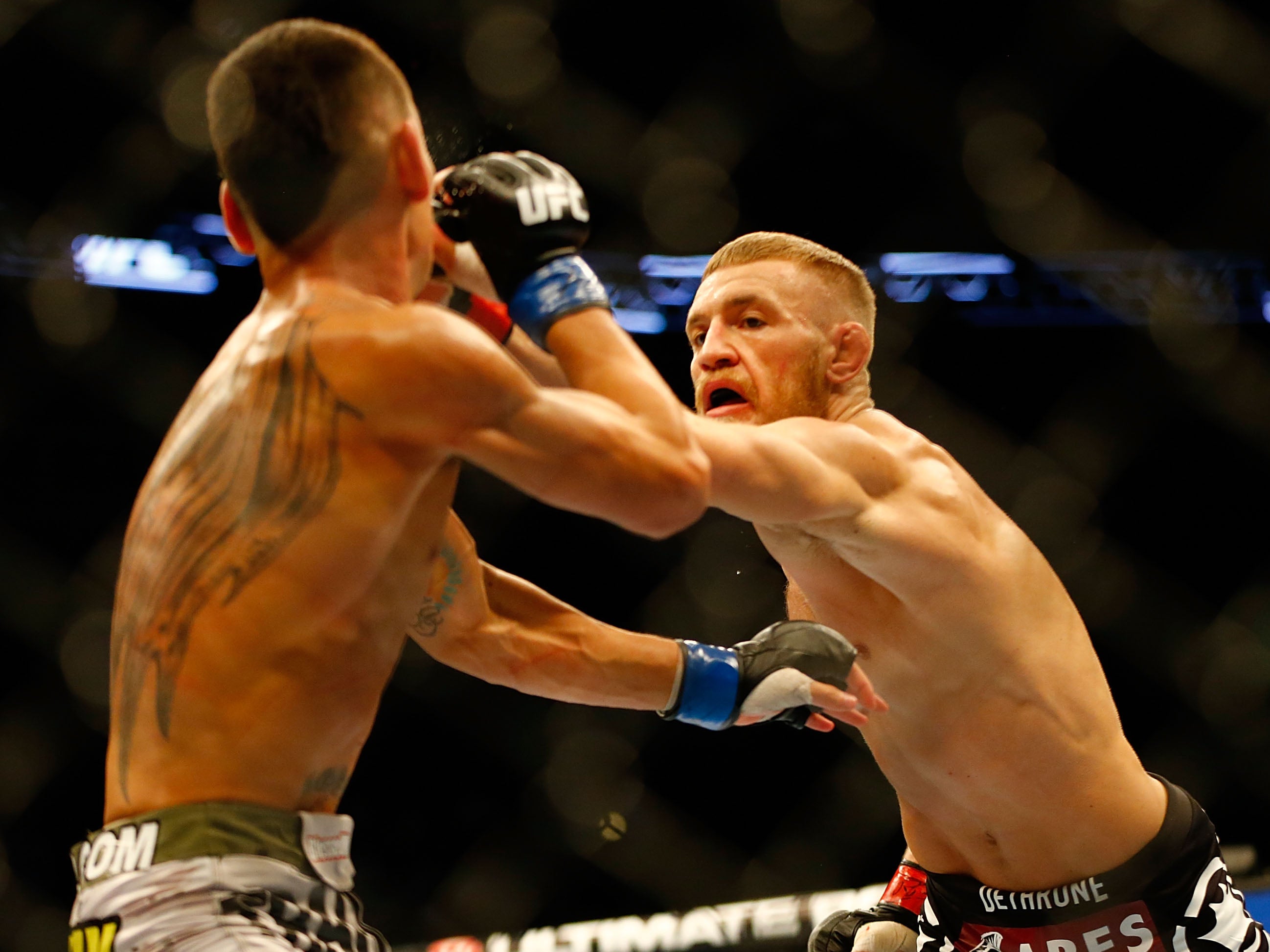 Conor McGregor punches Max Holloway in their featherweight bout at TD Garden