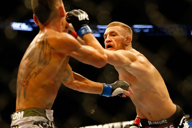 <p>Conor McGregor punches Max Holloway in their featherweight bout at TD Garden</p>