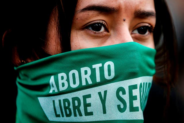 <p>An activist wears a trademark green handkerchief at a Bogota pro-choice rally last year </p>