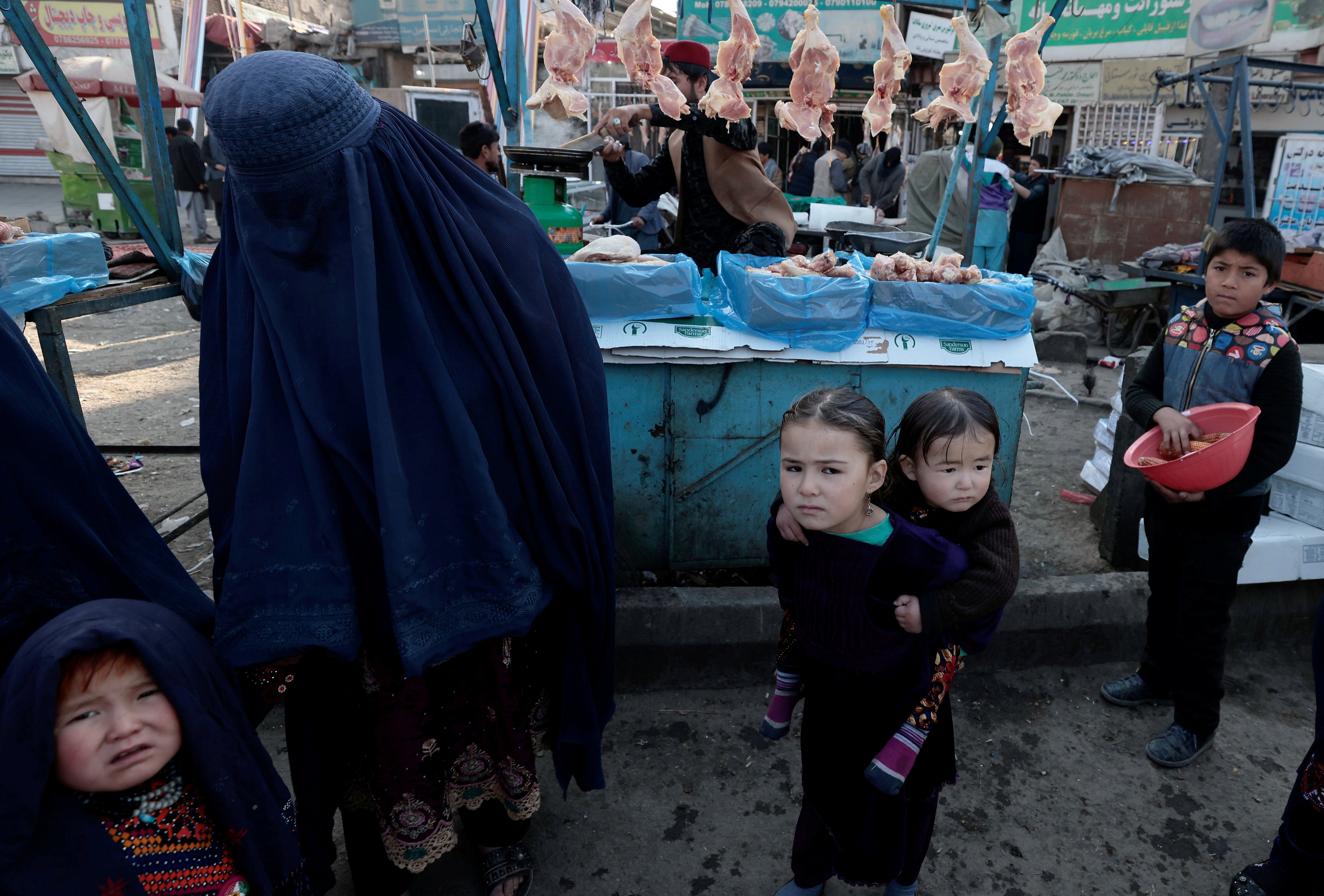 A mother shops with her children at a market in Kabul