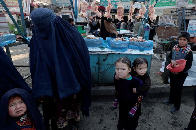 <p>A mother shops with her children at a market in Kabul</p>