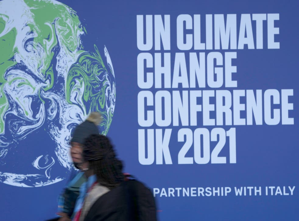 <p>Attendees walk past a banner at the venue where the COP26 climate conference will be held in Glasgow, Scotland. </p>