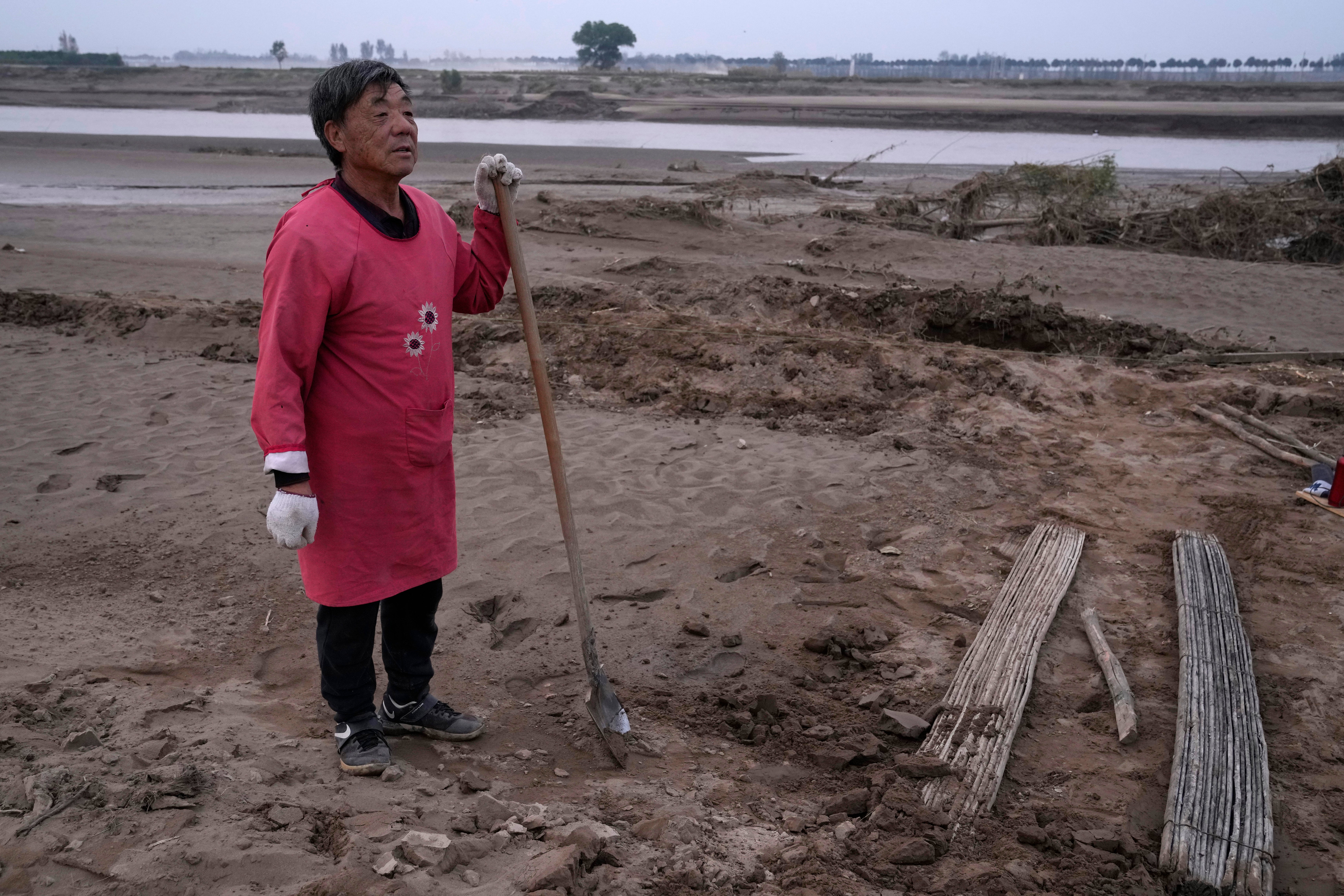 Wang Yue-tang stands near what used to be his peanut farm before torrential rains submerged the lowland leaving him with no summer harvest near Xubao village in central China’s Henan province in October 2021