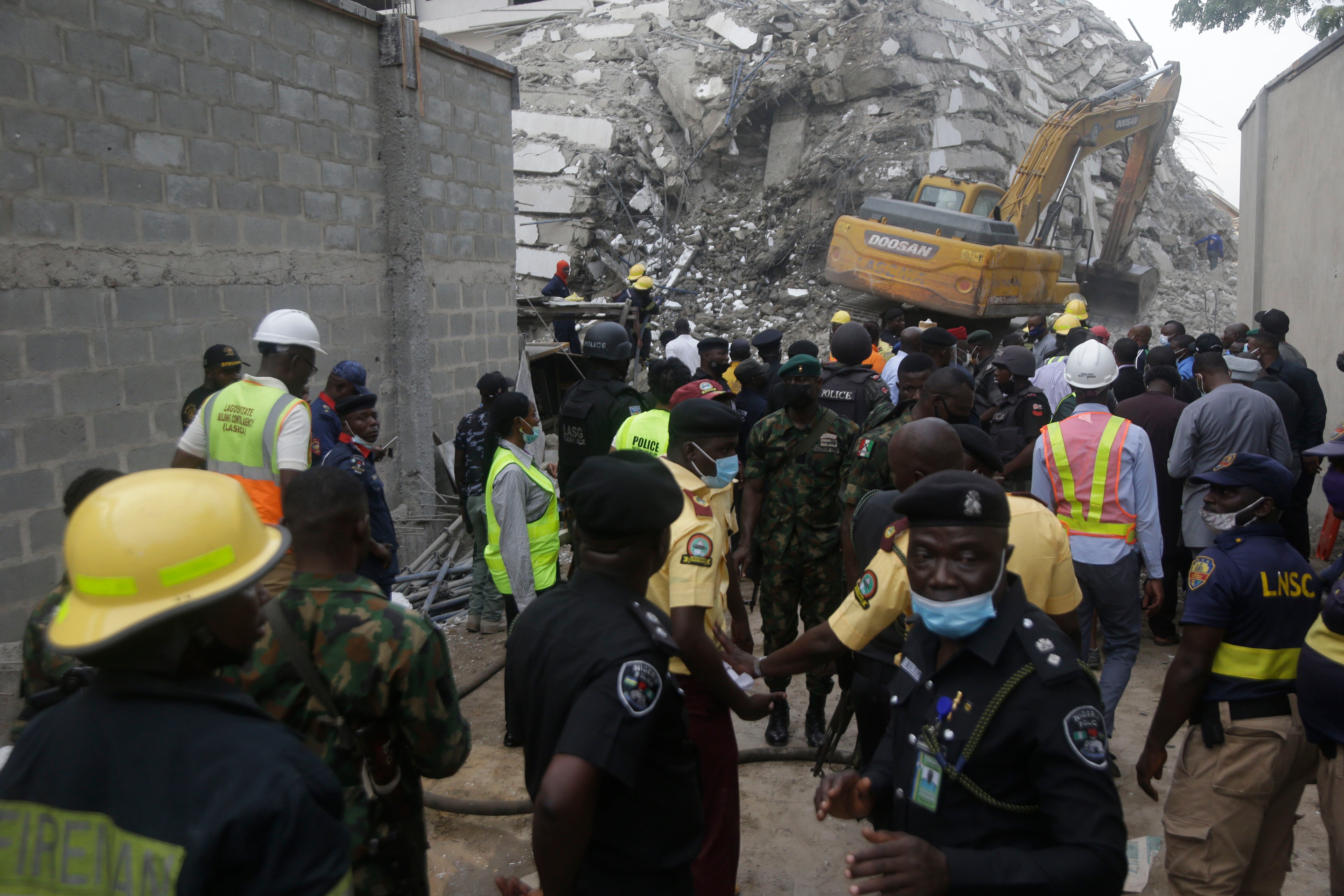 Security forces gather as rescue worker inspect the site of the collapsed 21-storey apartment building under construction in Lagos, Nigeria