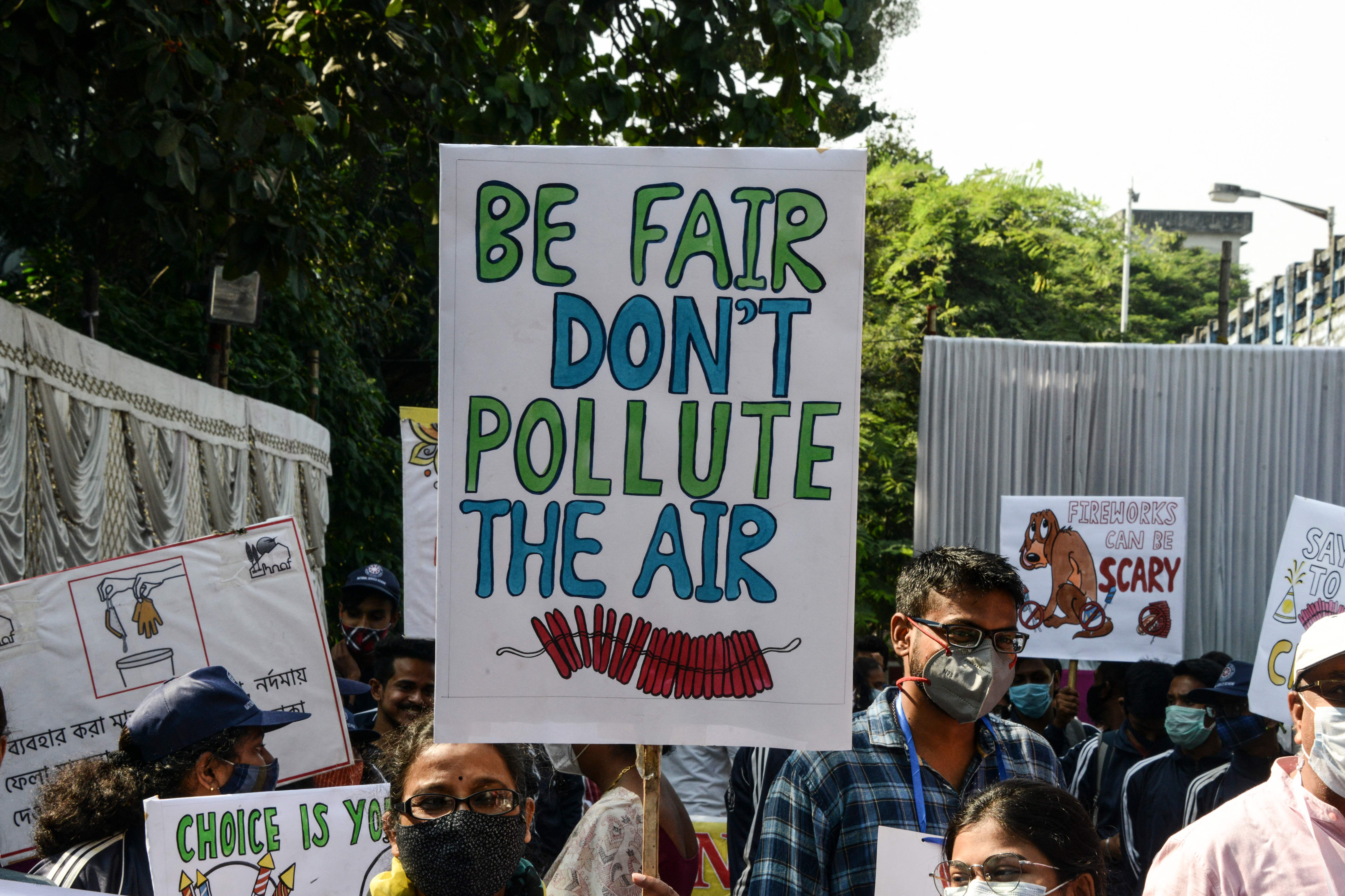People hold placards to raise awareness of air pollution caused by fireworks used during the celebrations for the upcoming Hindu festival of Diwali
