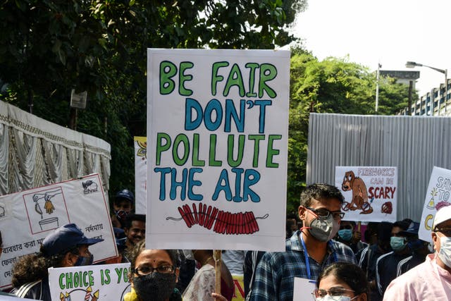Las personas sostienen pancartas para crear conciencia sobre la contaminación del aire causada por los petardos utilizados durante las celebraciones del próximo festival hindú de Diwali.
