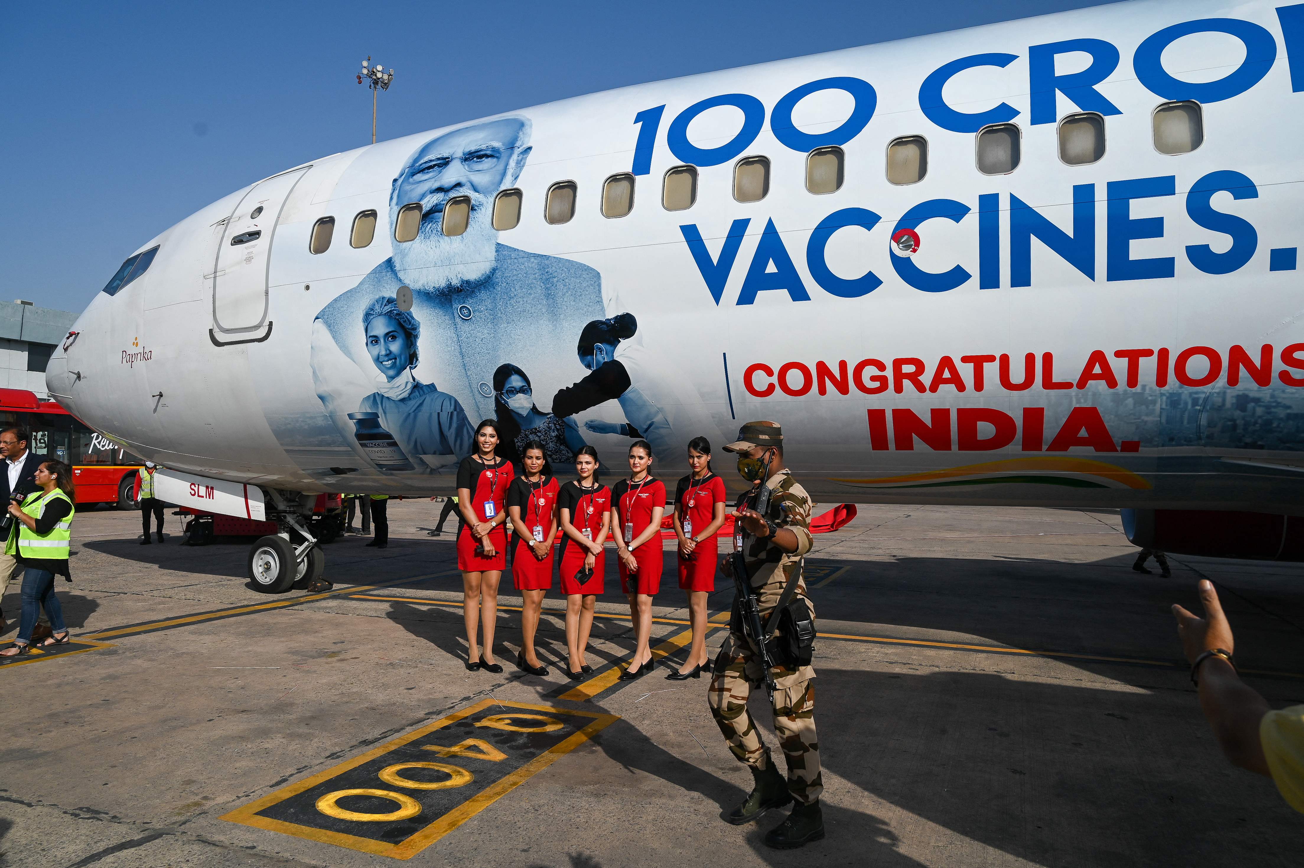 Air stewardesses pose for picture with during the unveiling of a SpiceJet Boeing 737 design celebrating India's administering its billionth Covid-19 vaccine dose during an unveiling event at the Indira Gandhi International Airport in New Delhi on October 21, 2021