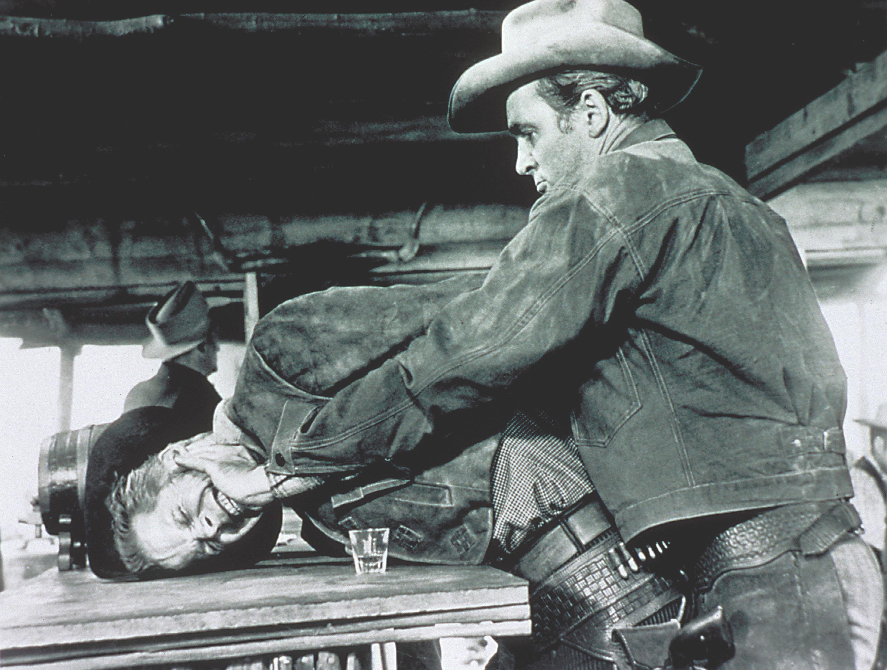 Stewart as Lin McAdam smashes Dan Duryea (Waco Johnnie Dean)’s face into a bar table in Anthony Mann’s Western ‘Winchester ’73’ (1950), but even here, you give him the benefit of the doubt