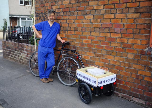 <p>Jet McDonald is transporting a block of ice with him as he cycles to represent the melting ice caps </p>