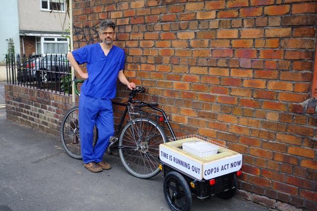 <p>Jet McDonald is transporting a block of ice with him as he cycles to represent the melting ice caps </p>