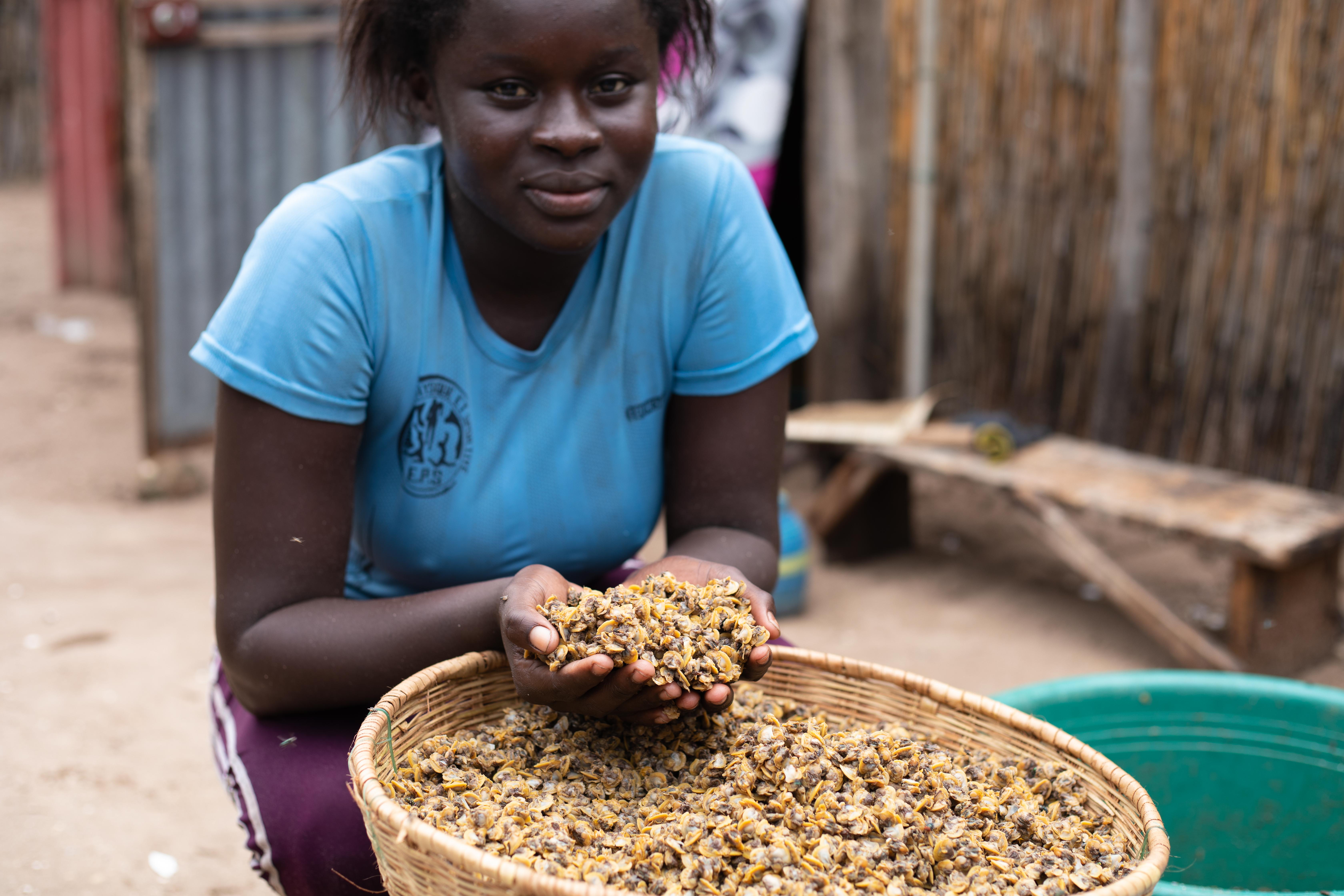 Coumba Manka, 19, a fish processor, holds cockles that have been removed from their shell at a community in Joal-Fadiouth