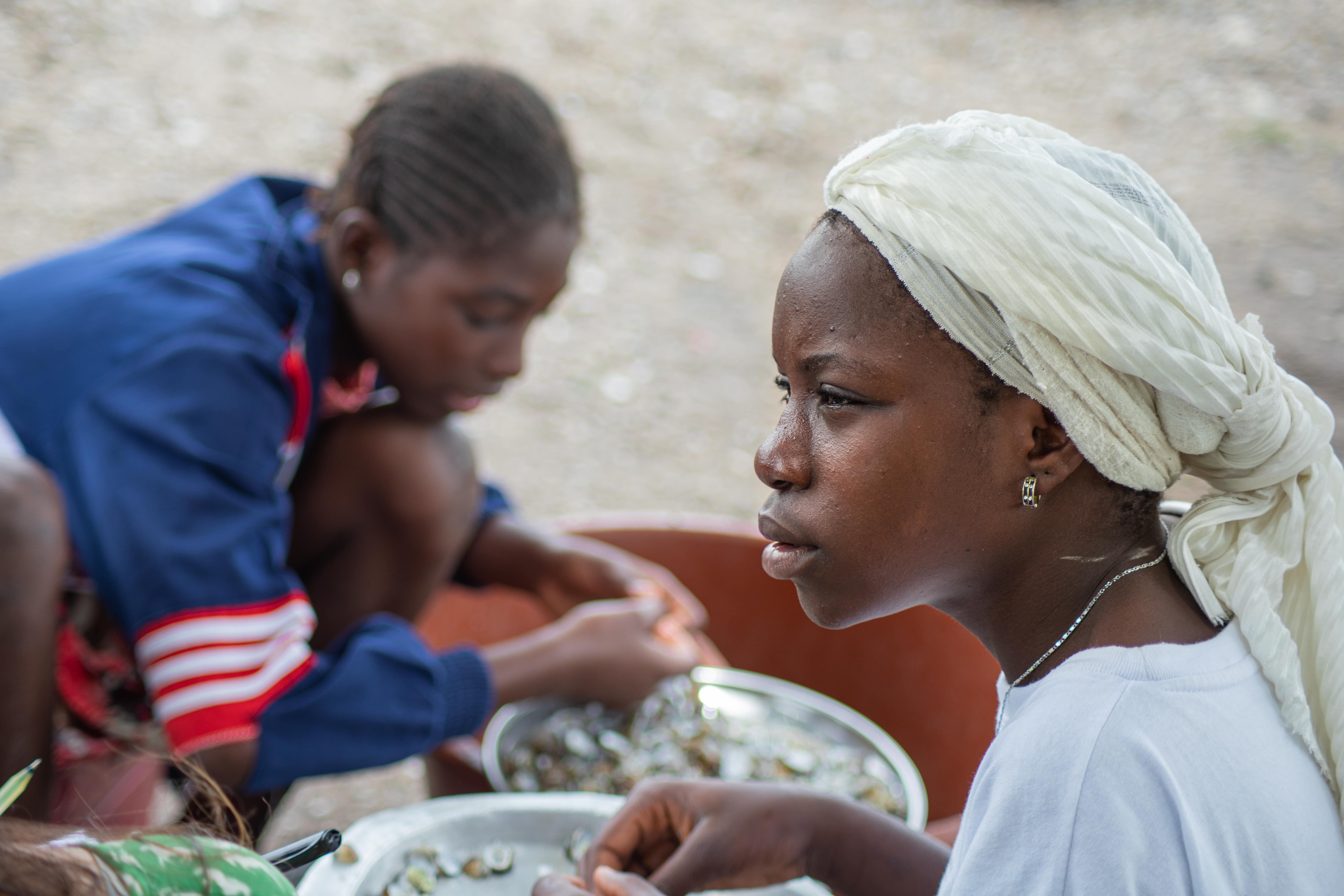 A young woman processes fish at a community in Joal-Fadiouth