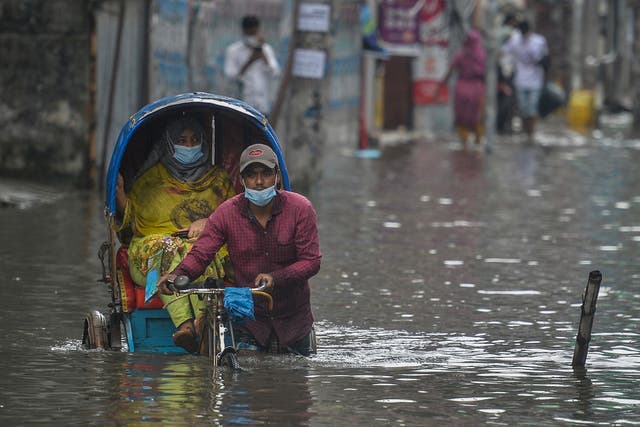 <p>A rickshaw puller wades through a waterlogged street carrying passengers after a heavy downpour in Dhaka, Bangladesh </p>