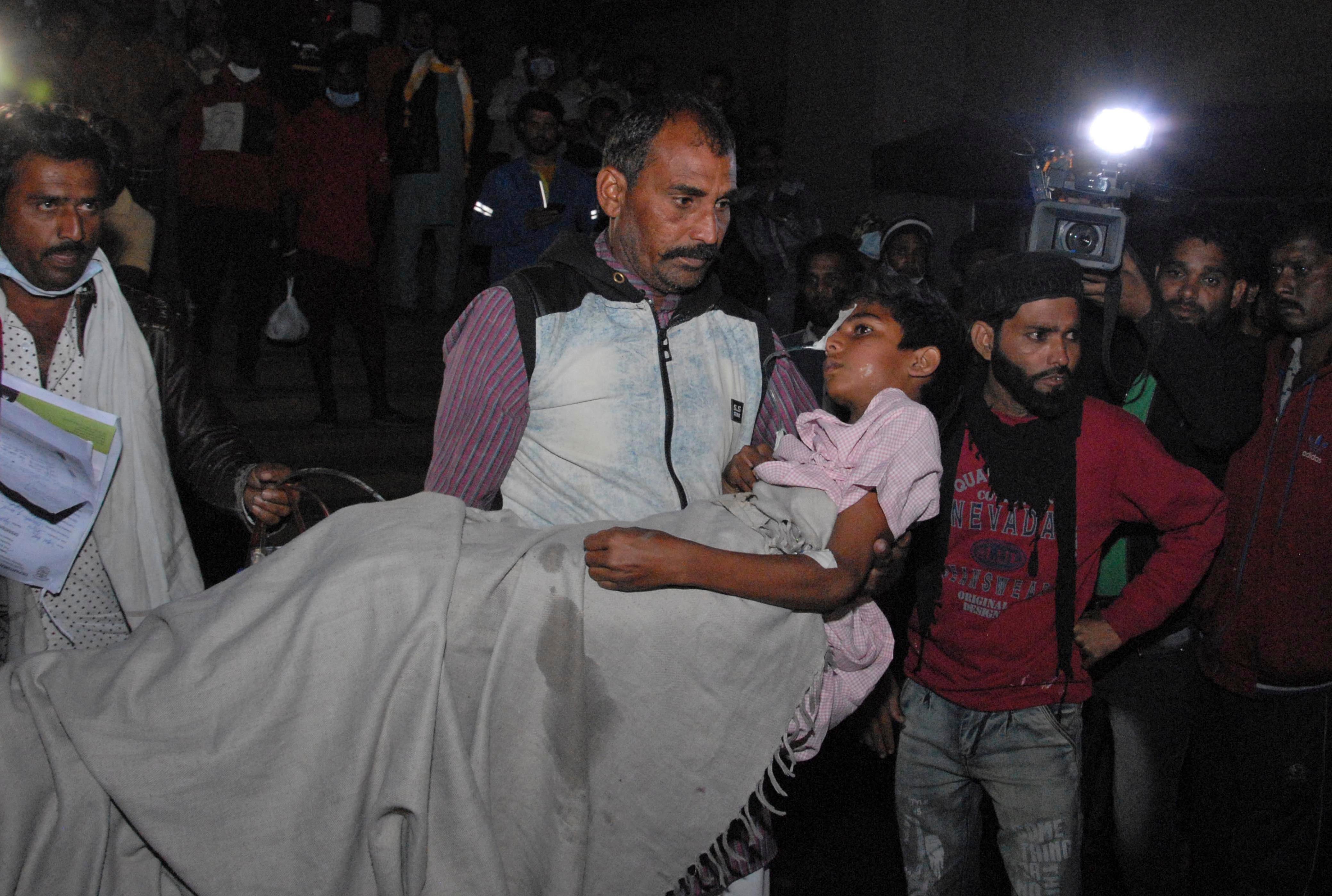 A man carries a child out from the Kamla Nehru Children's Hospital after a fire in the newborn care unit of the hospital killed four infants, in Bhopal, India