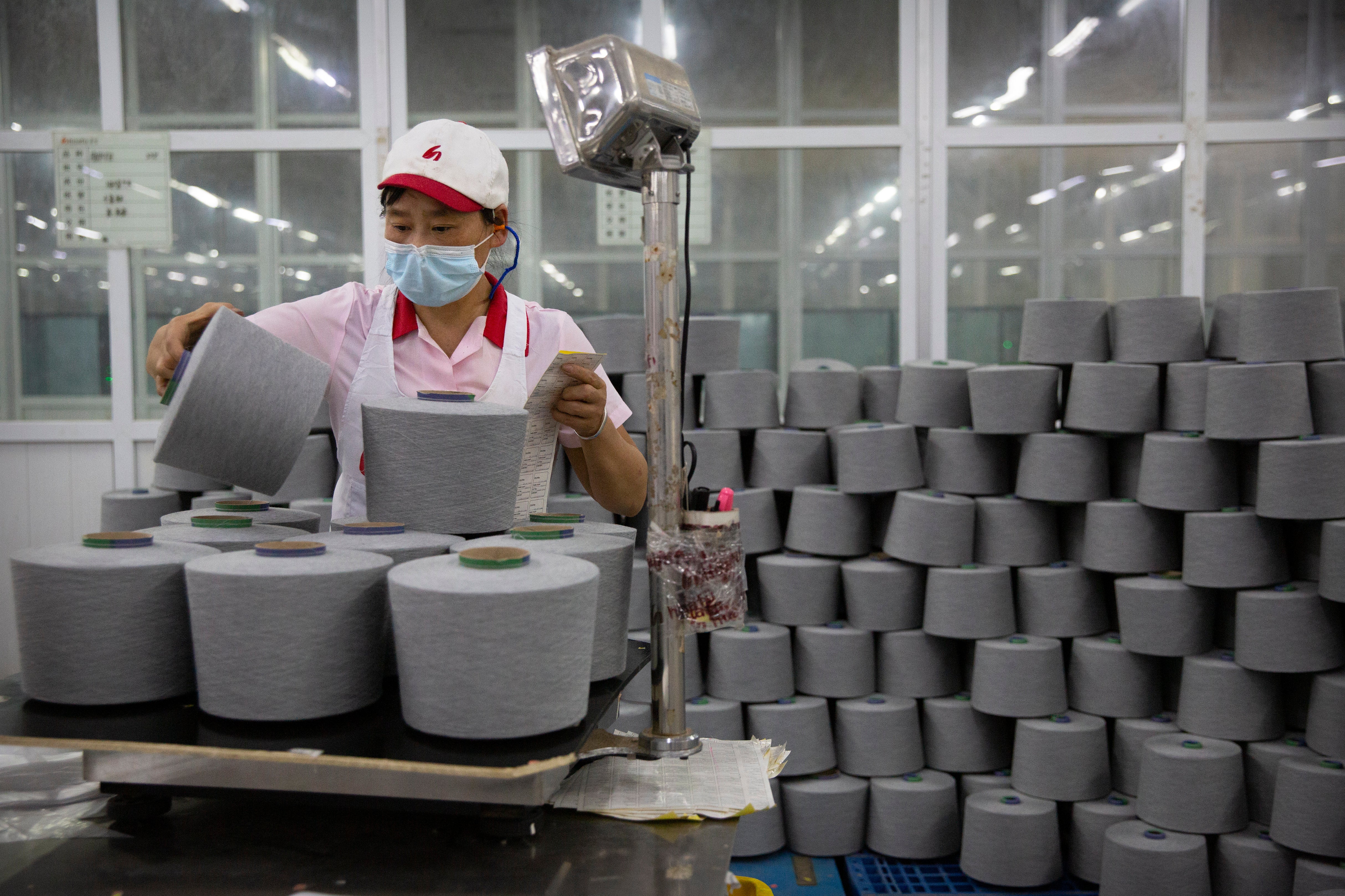 A worker packages spools of cotton yarn at a Huafu Fashion plant, as seen during a government-organised trip for foreign journalists, in Aksu in western China's Xinjiang Uyghur