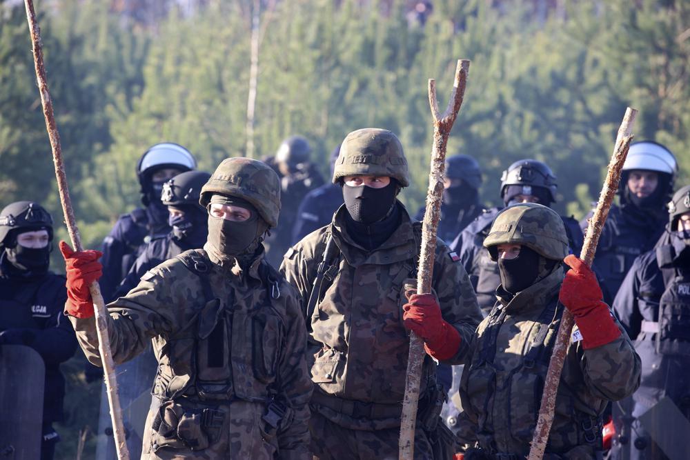Polish police and border guards stand near barbed wire to stop migrants from the Middle East and elsewhere gathering at the Belarus-Poland border near Grodno, Belarus, Tuesday, 9 November