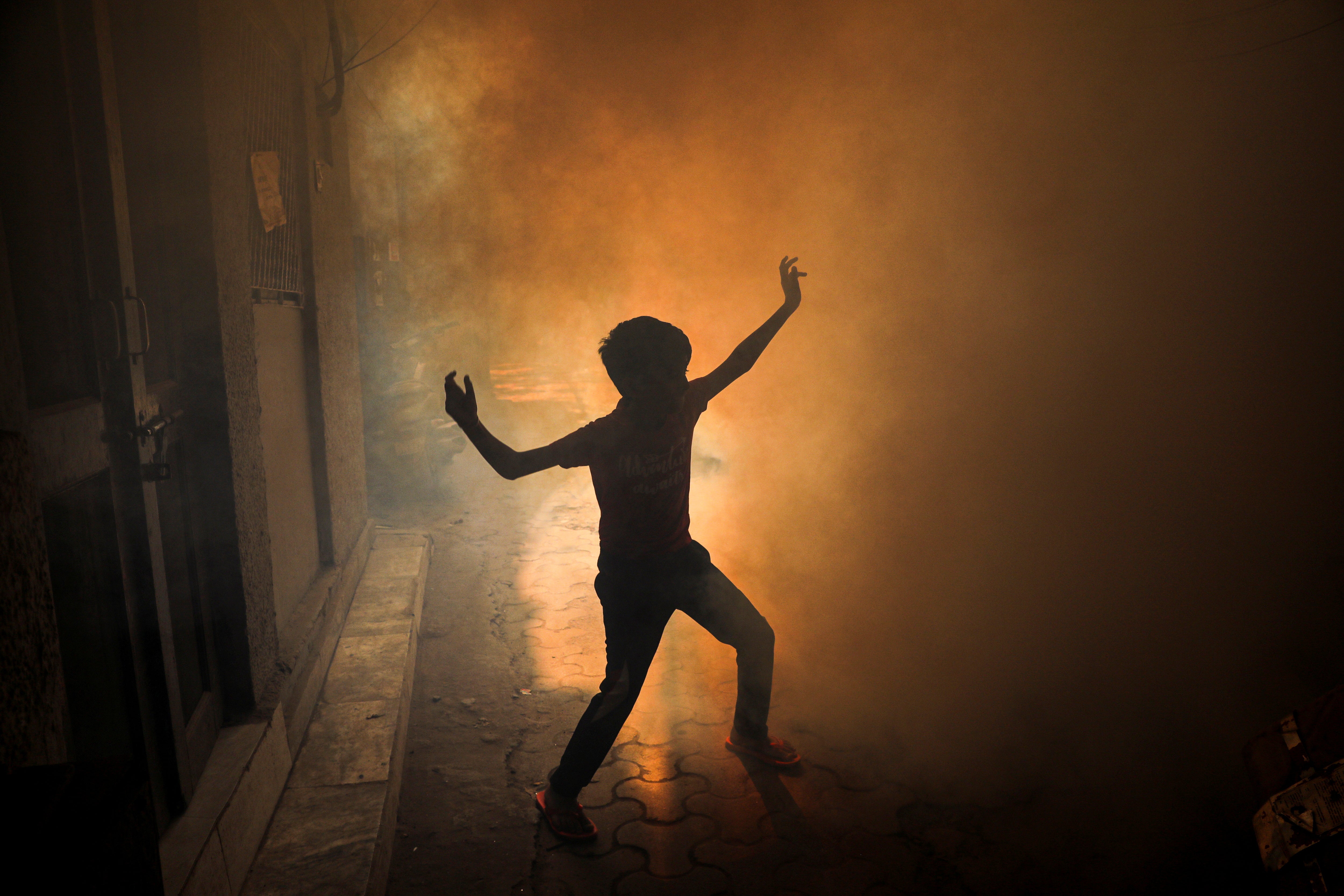 A child plays during a fumigation drive conducted by the municipal corporation as dengue cases surge in Delhi