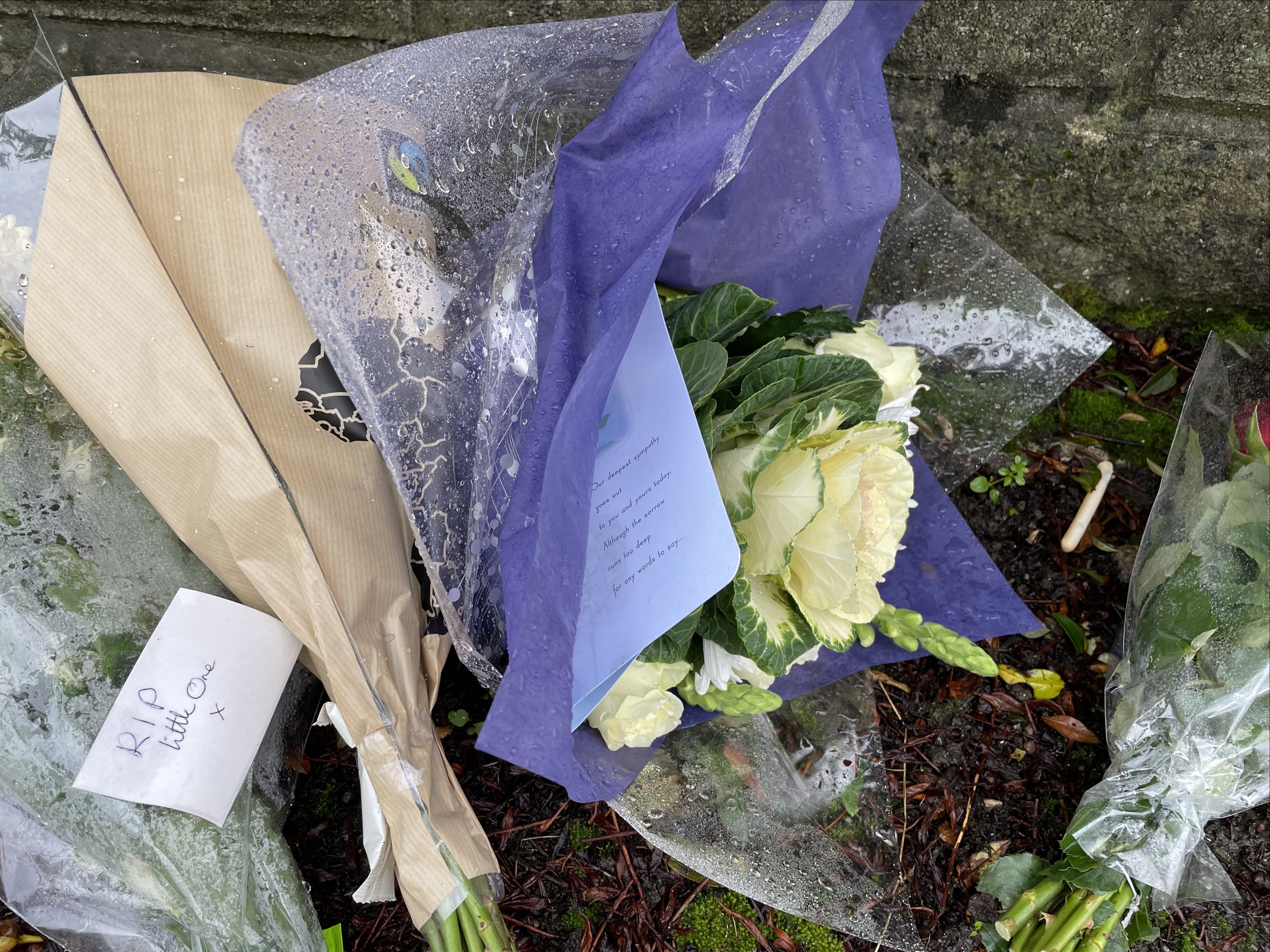 Flowers with a card reading ‘RIP little one’ are left outside the house where Jack, 10, died